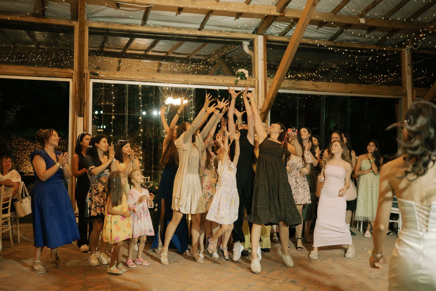 Wedding guests dance and celebrate together on a rustic wooden dance floor during an evening reception.