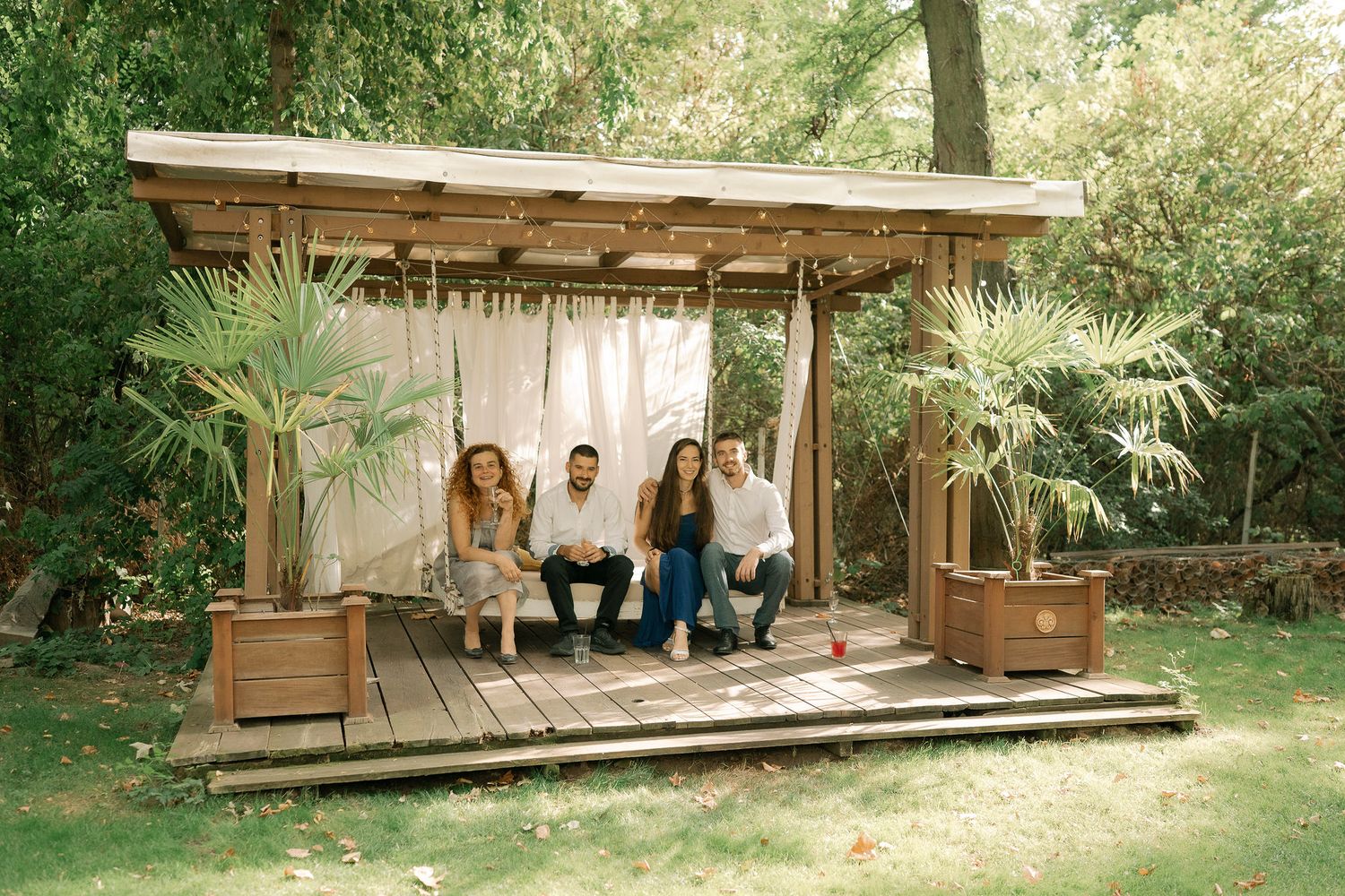 Modern wooden pavilion structure in a natural outdoor setting surrounded by lush greenery and trees.