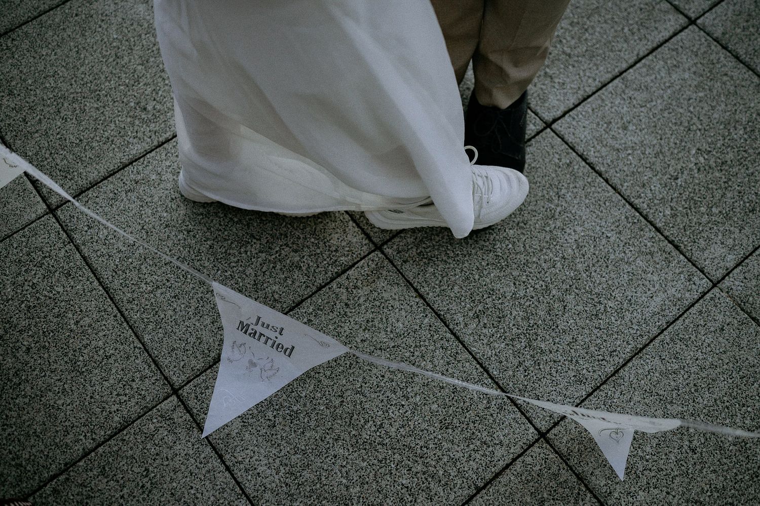 White triangle banners hang above a stone patio during a wedding celebration.