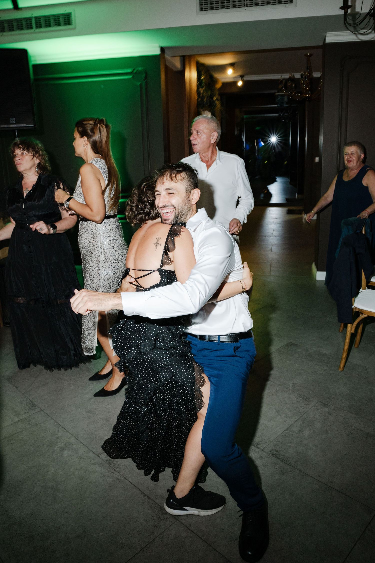Couples dancing energetically at a wedding reception with green lighting effects.