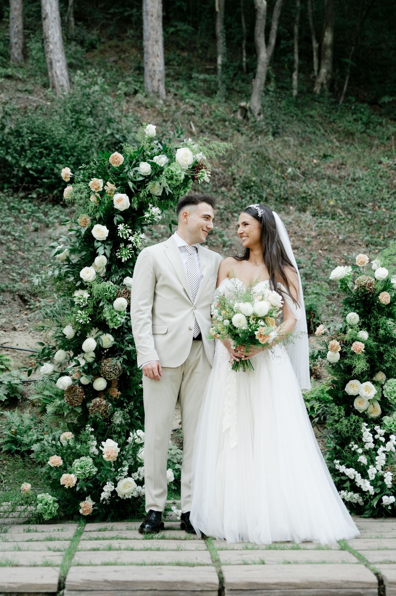 Outdoor wedding portrait on stone steps with luxurious white rose floral installation.