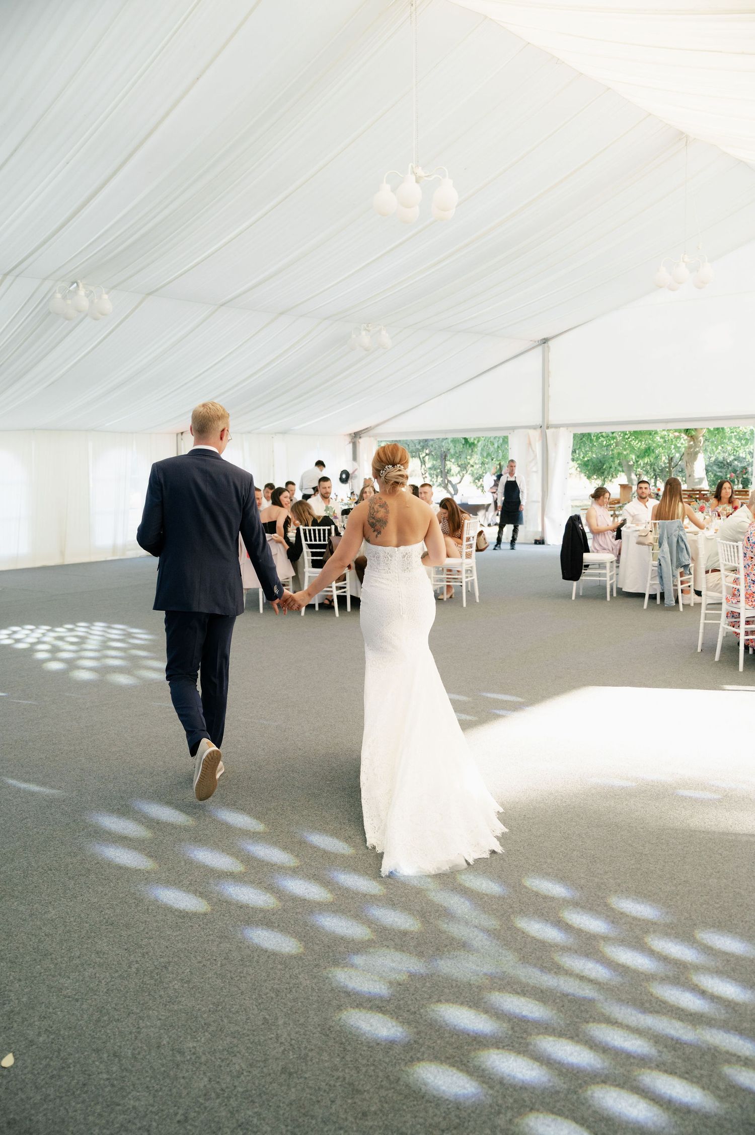 Wedding reception tent interior with spotlights creating circular patterns on grey carpet.