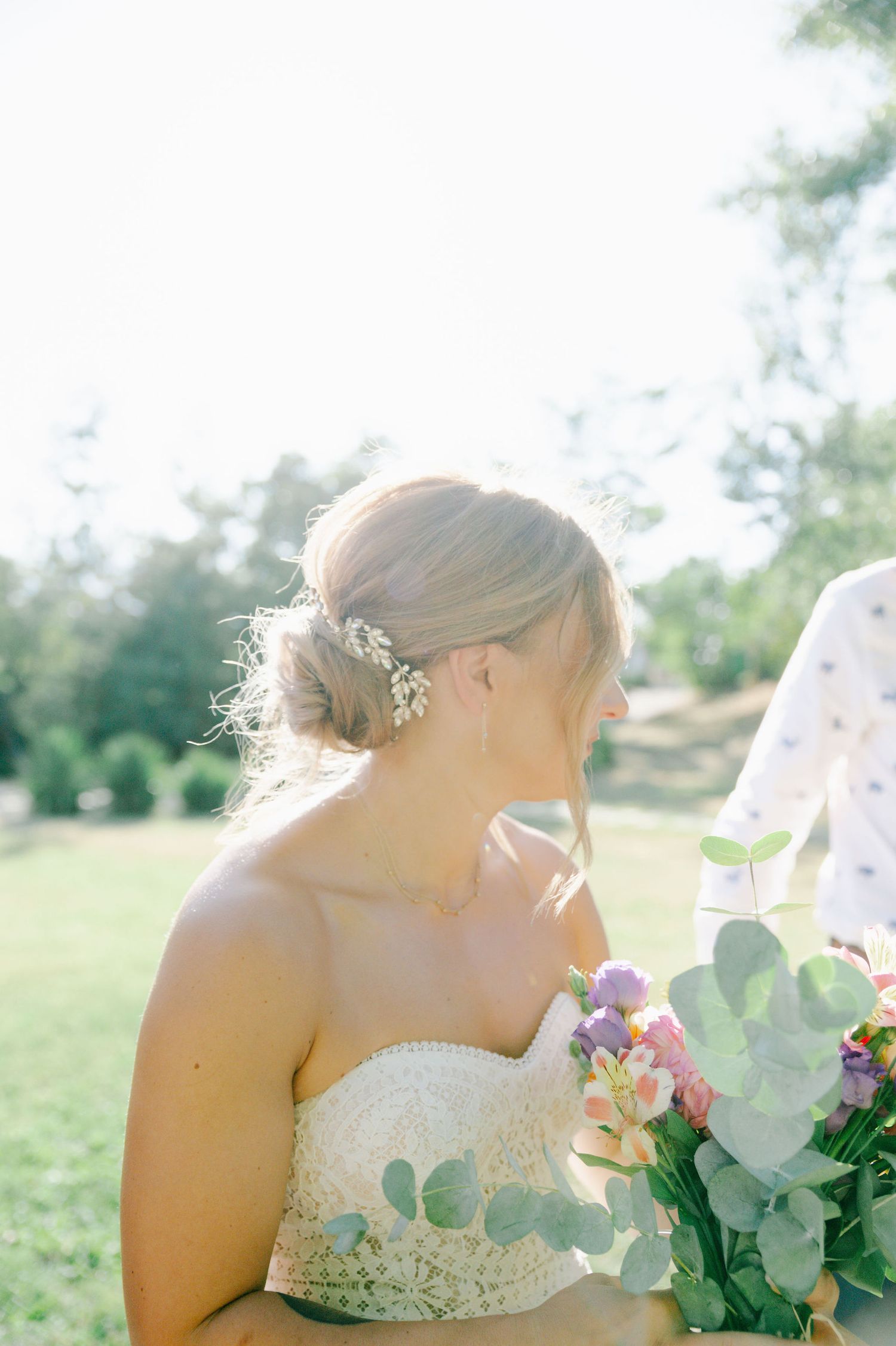Close-up of a white wedding dress with delicate lace details and floral bouquet.
