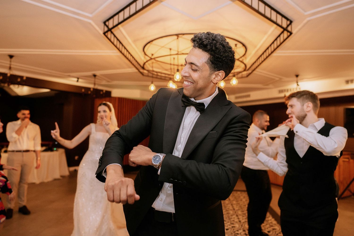 Formal event guests performing synchronized dance moves in a ballroom setting.