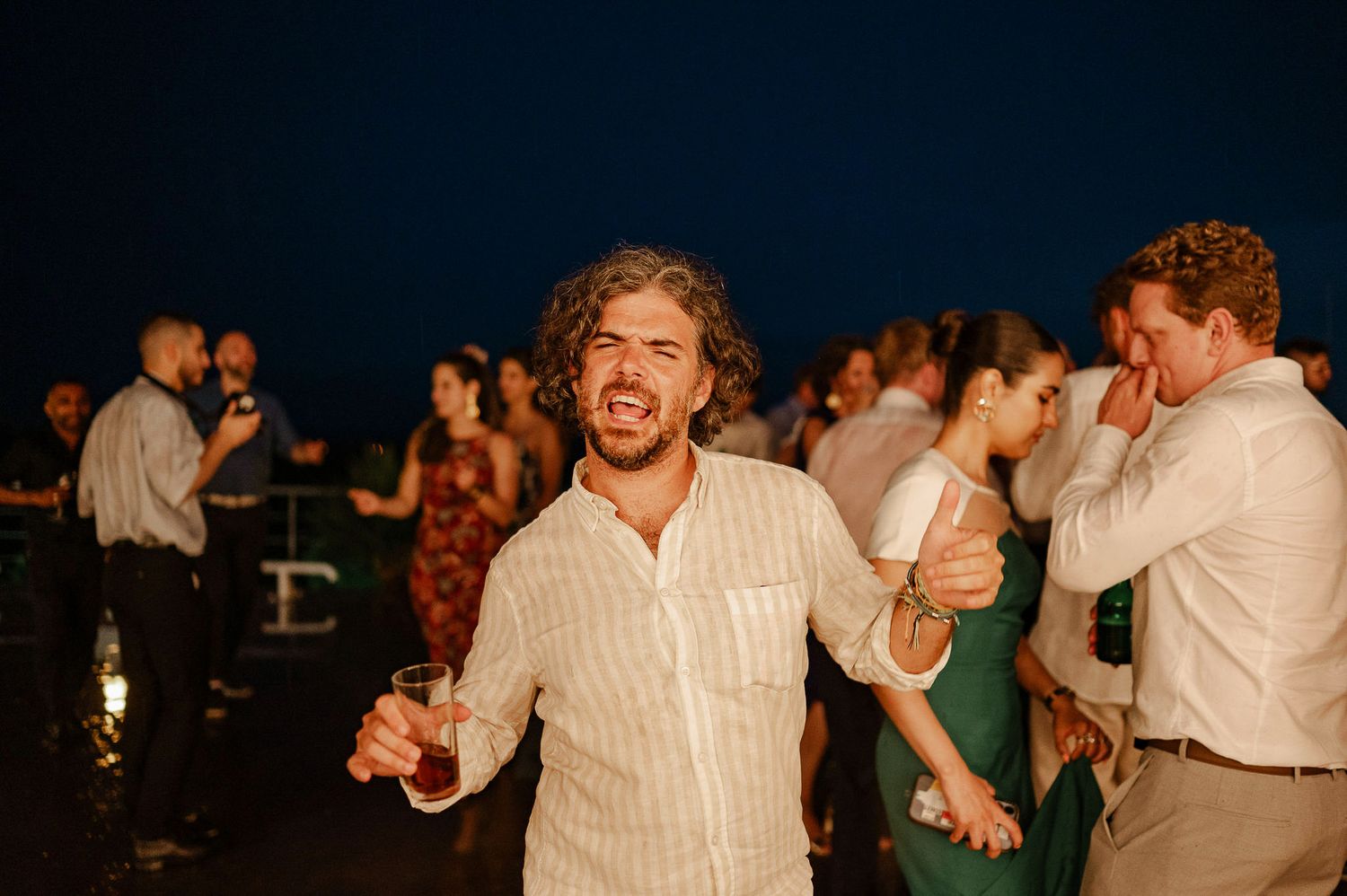 Joyful celebration with dancing guests at an outdoor evening reception.