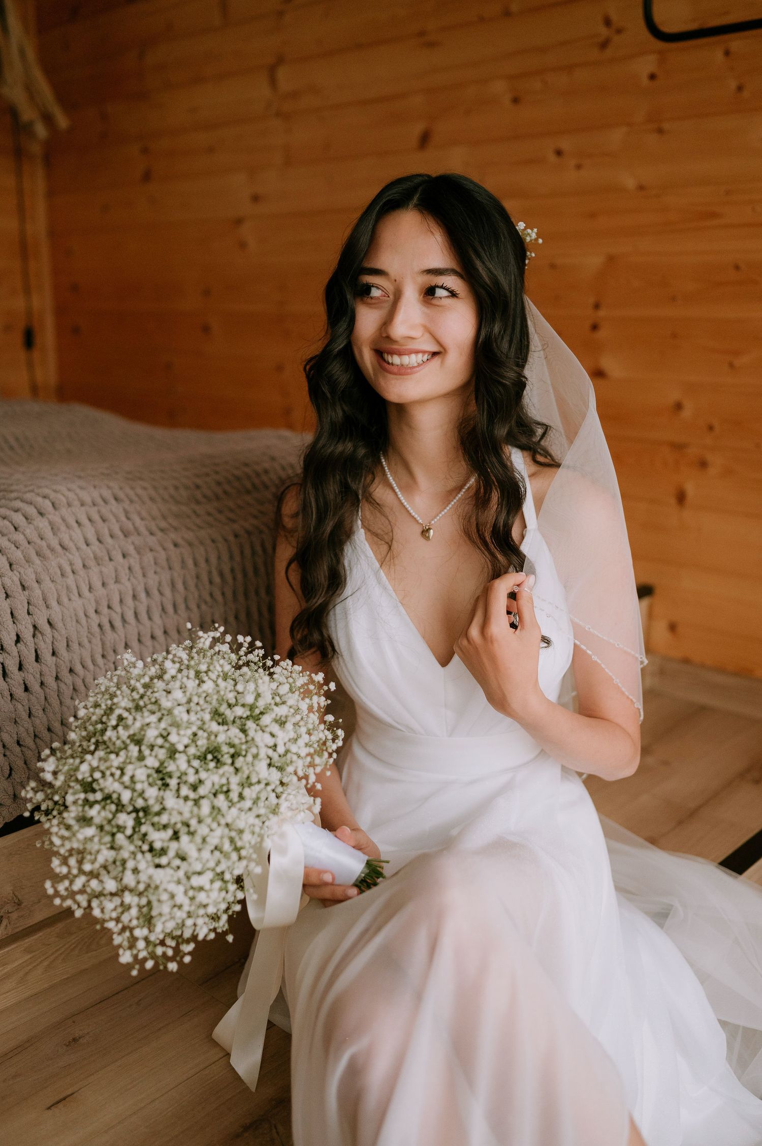 Delicate bridal photo with baby's breath bouquet and white gown in natural lighting.
