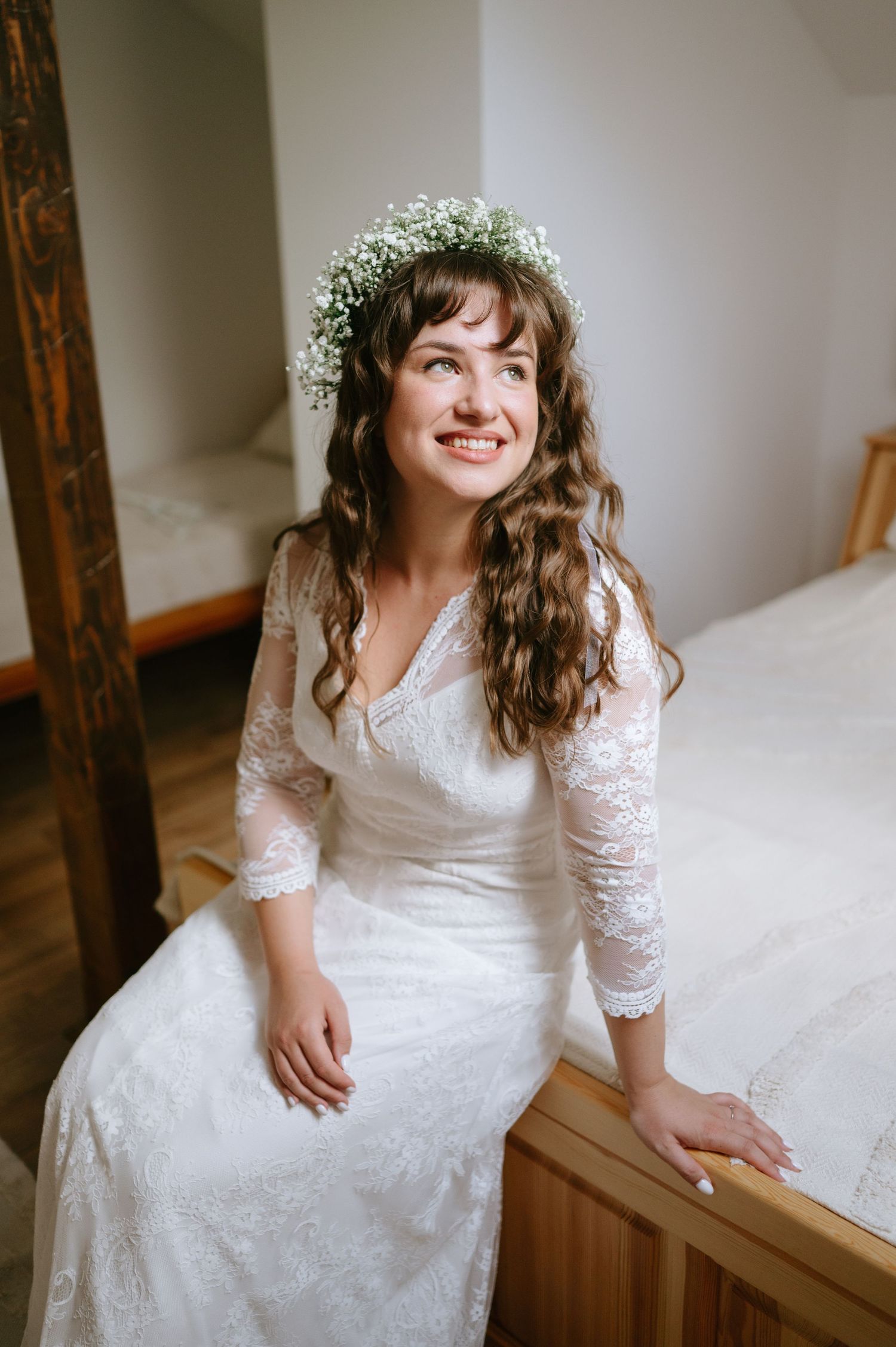 A romantic bridal portrait featuring a white lace dress and floral crown against a neutral background.