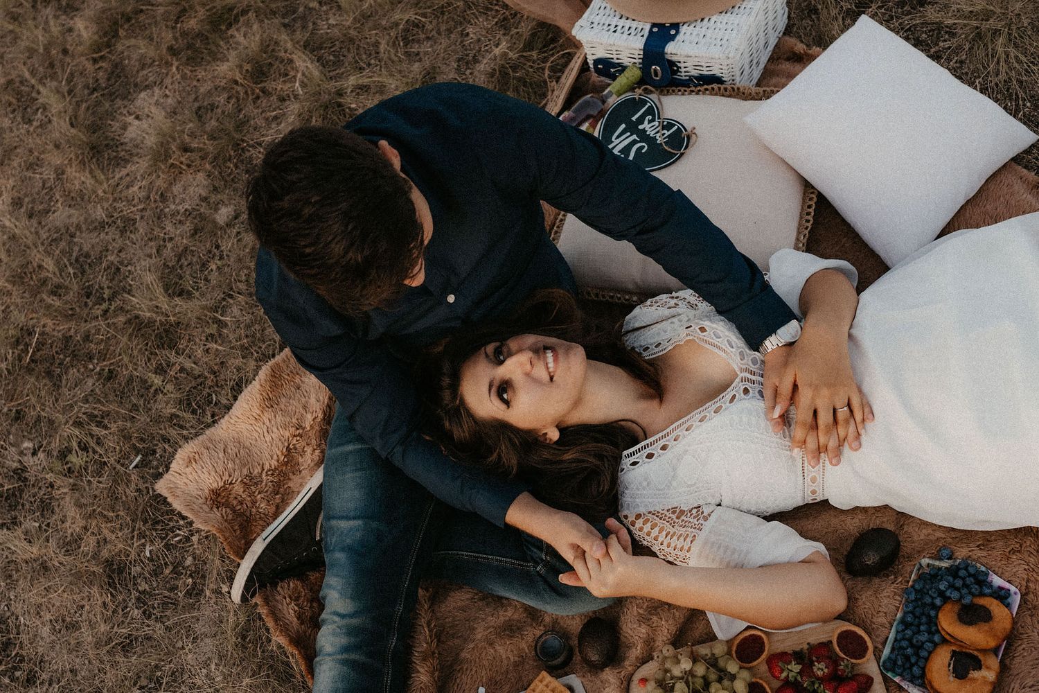 Couple enjoying wine and snacks while relaxing on a picnic blanket.