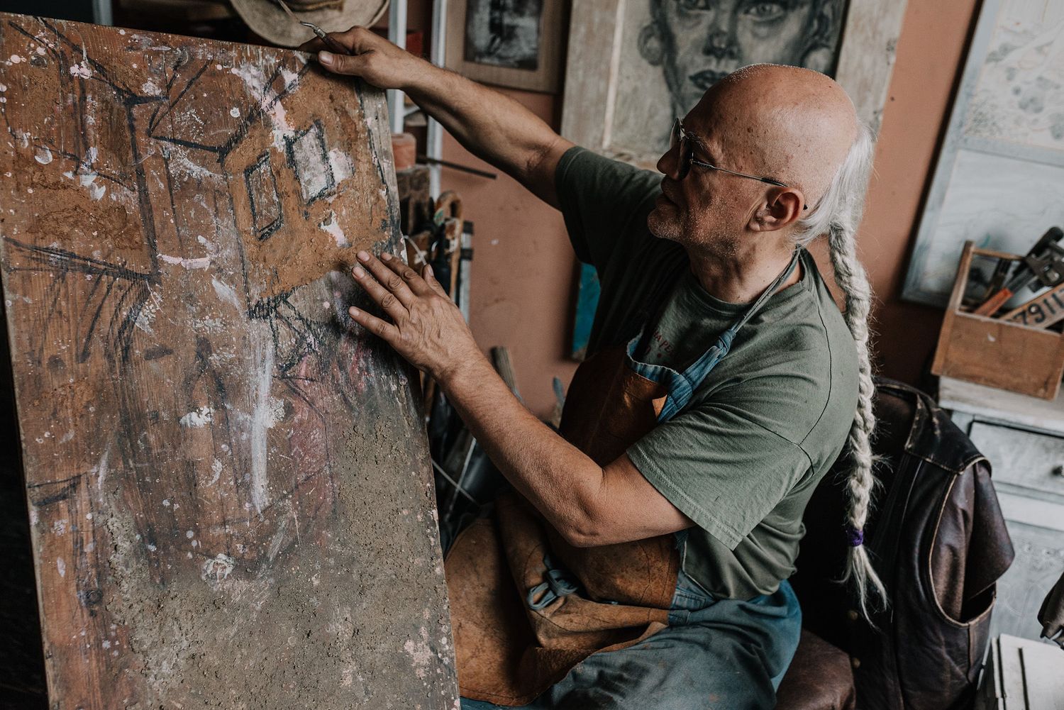 Artist working with weathered materials in an outdoor workspace.