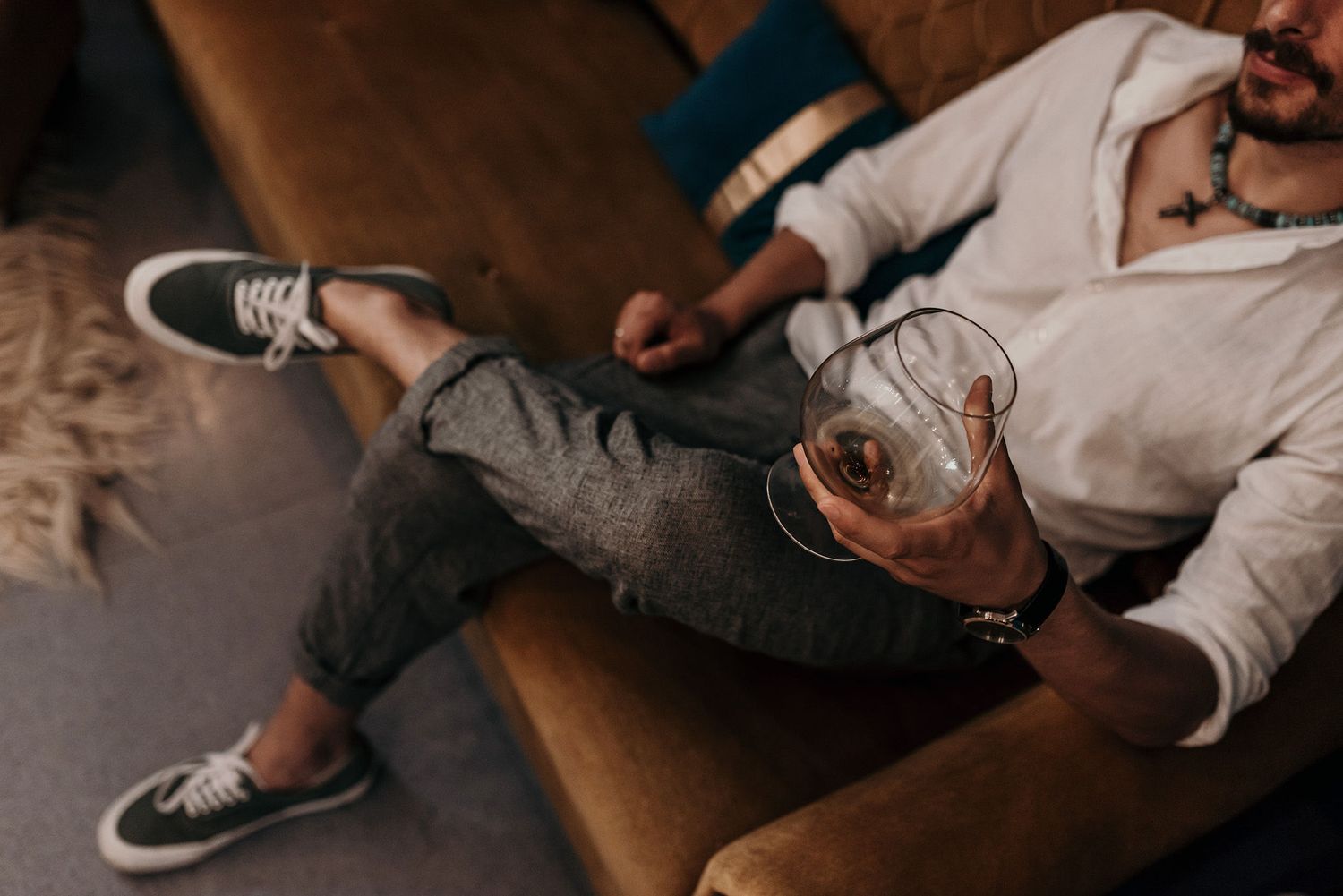 Person lounging on leather couch in dimly lit room with feet up and casual attire.