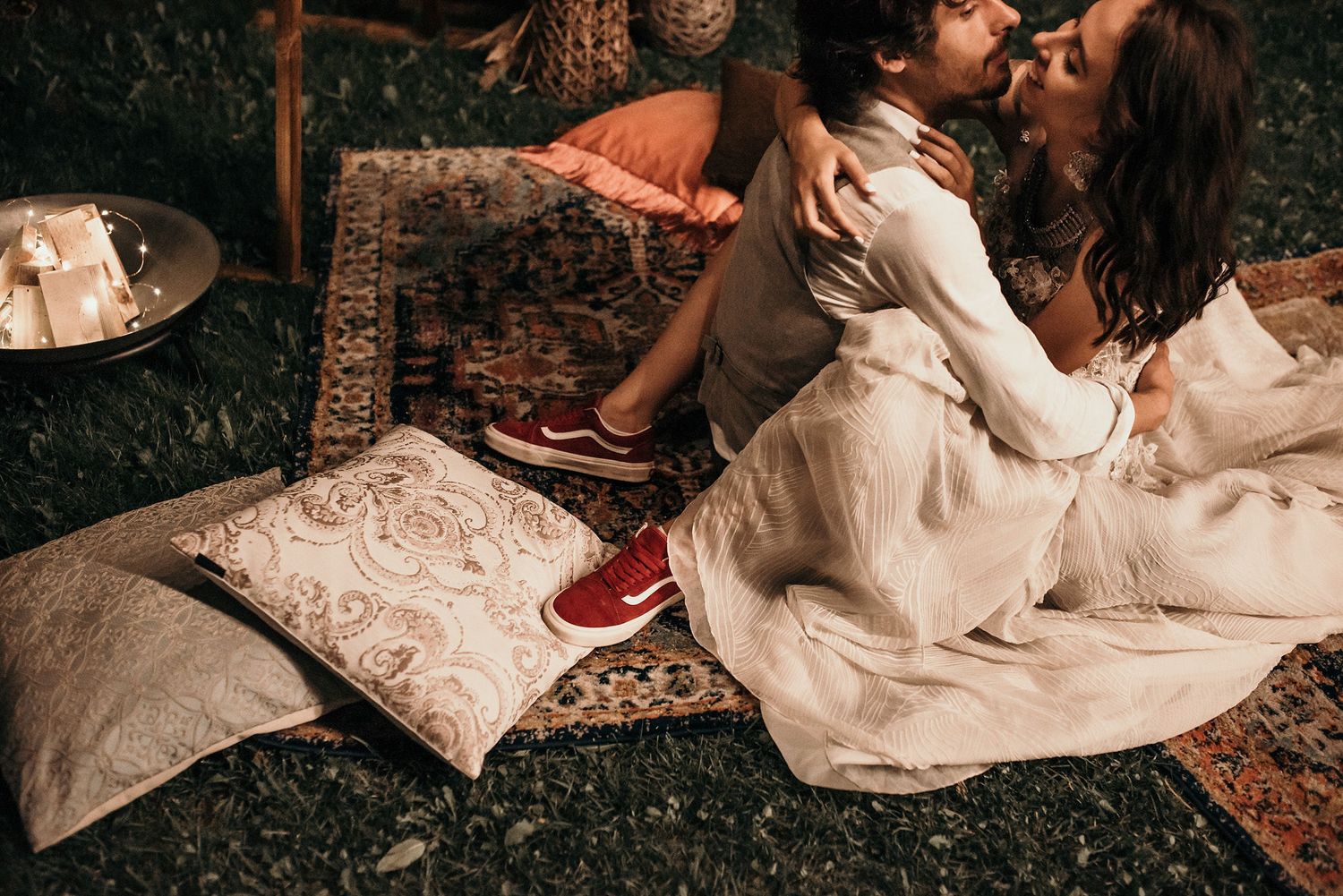 Romantic boho picnic setup with pillows and candles on a vintage rug outdoors.