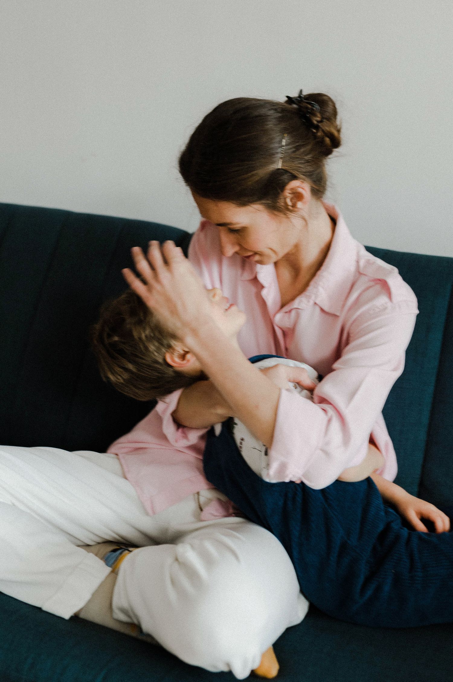 Two people in pink and white outfits share an intimate moment on a navy blue couch.