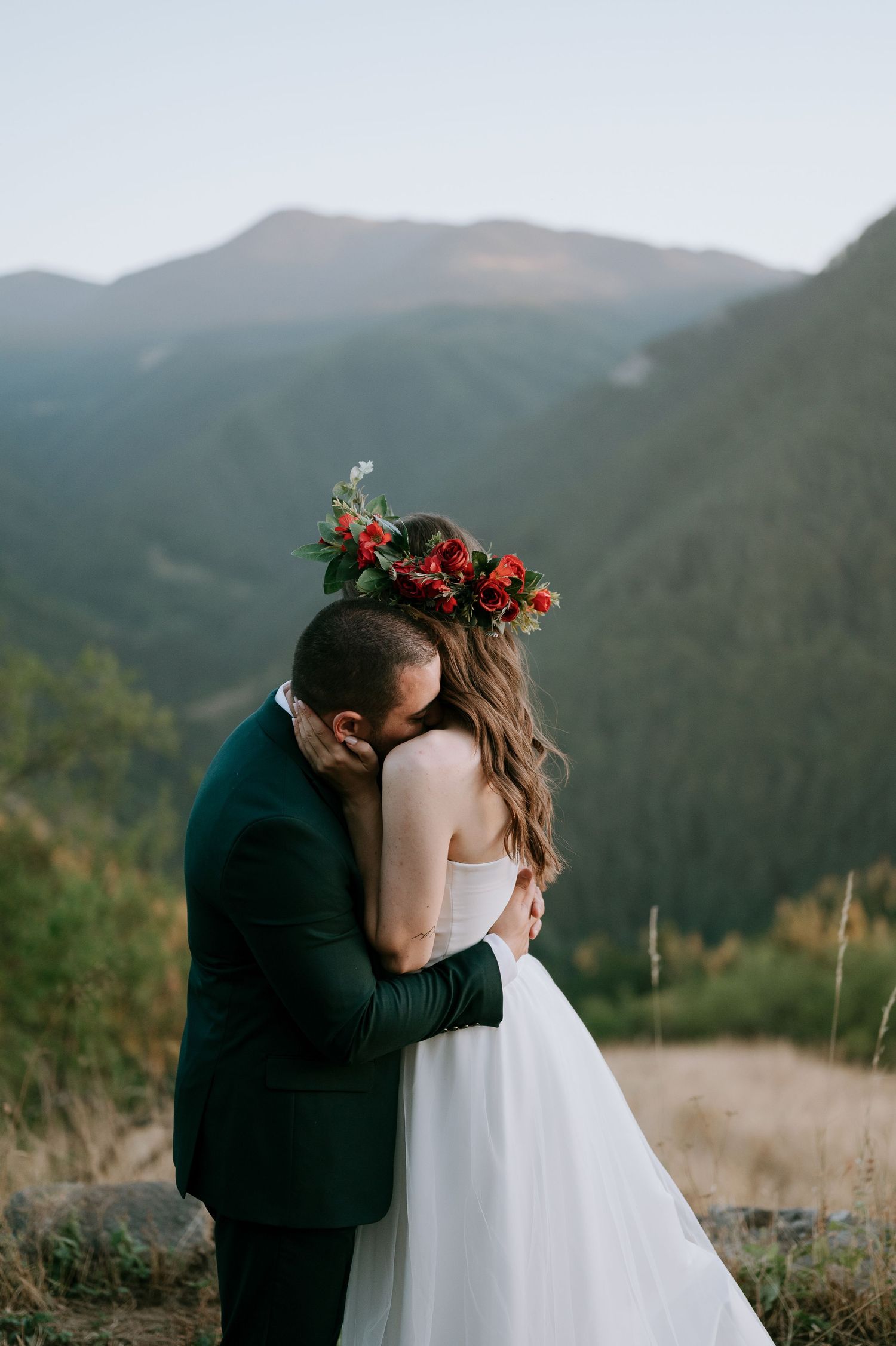 A tender wedding embrace photographed against dramatic mountain scenery at golden hour.