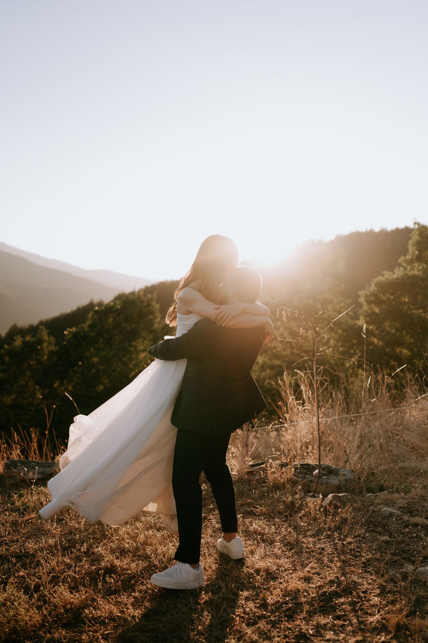 A celebratory lift during a mountain wedding photoshoot at sunset.