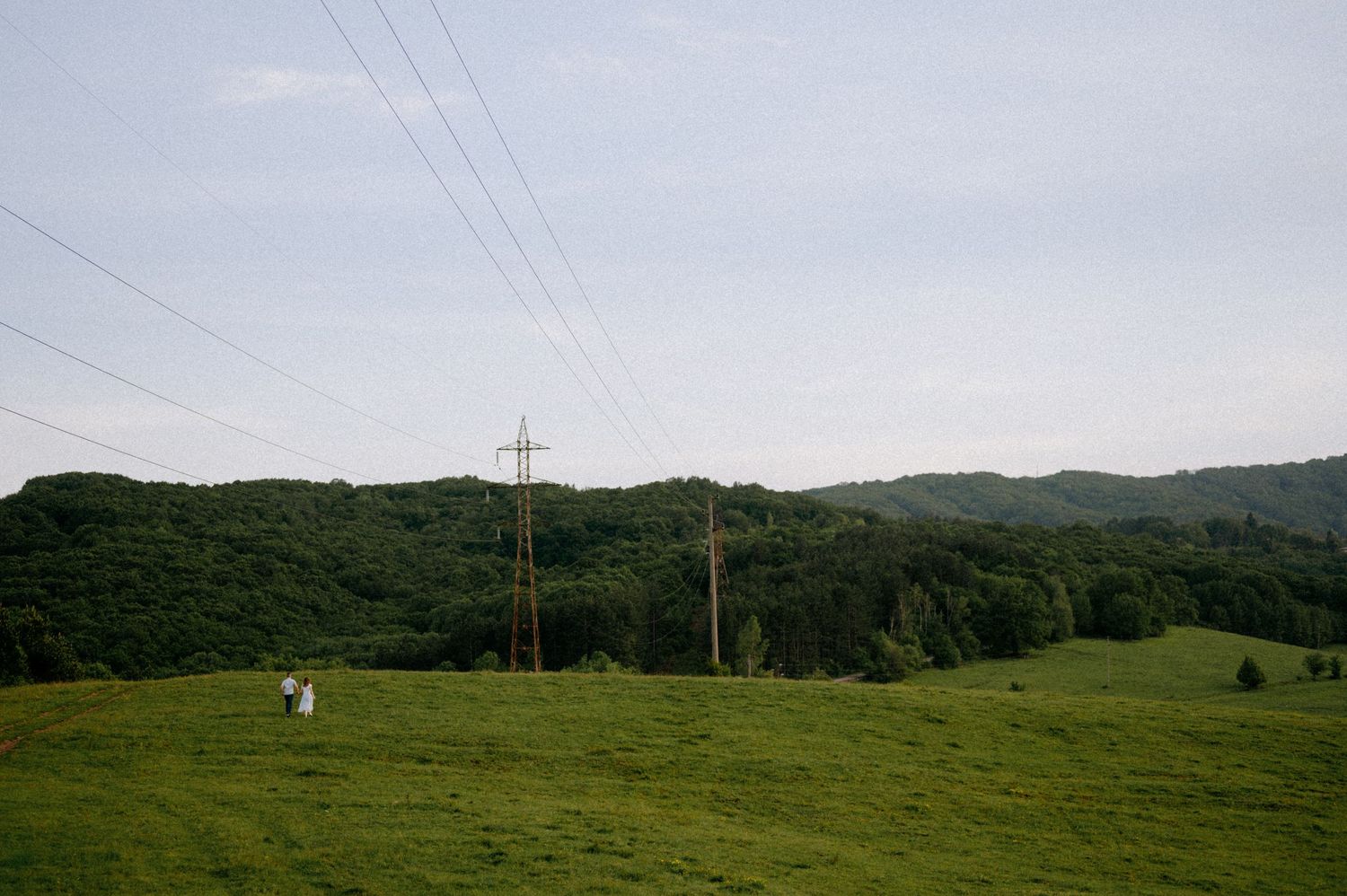 Pastoral landscape with electrical infrastructure crossing over green rolling hills.