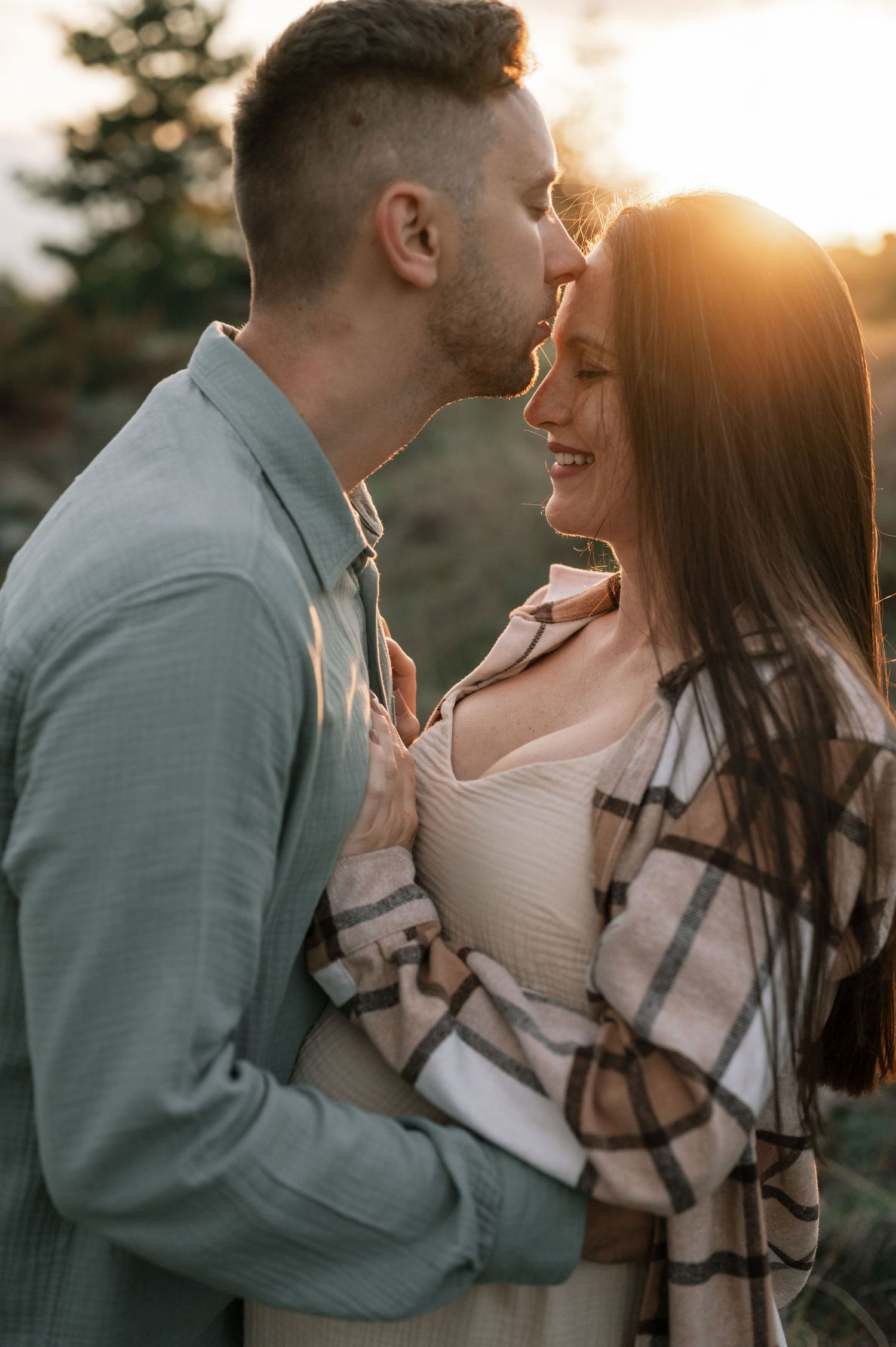 Intimate moment between couple during golden hour photoshoot in nature.