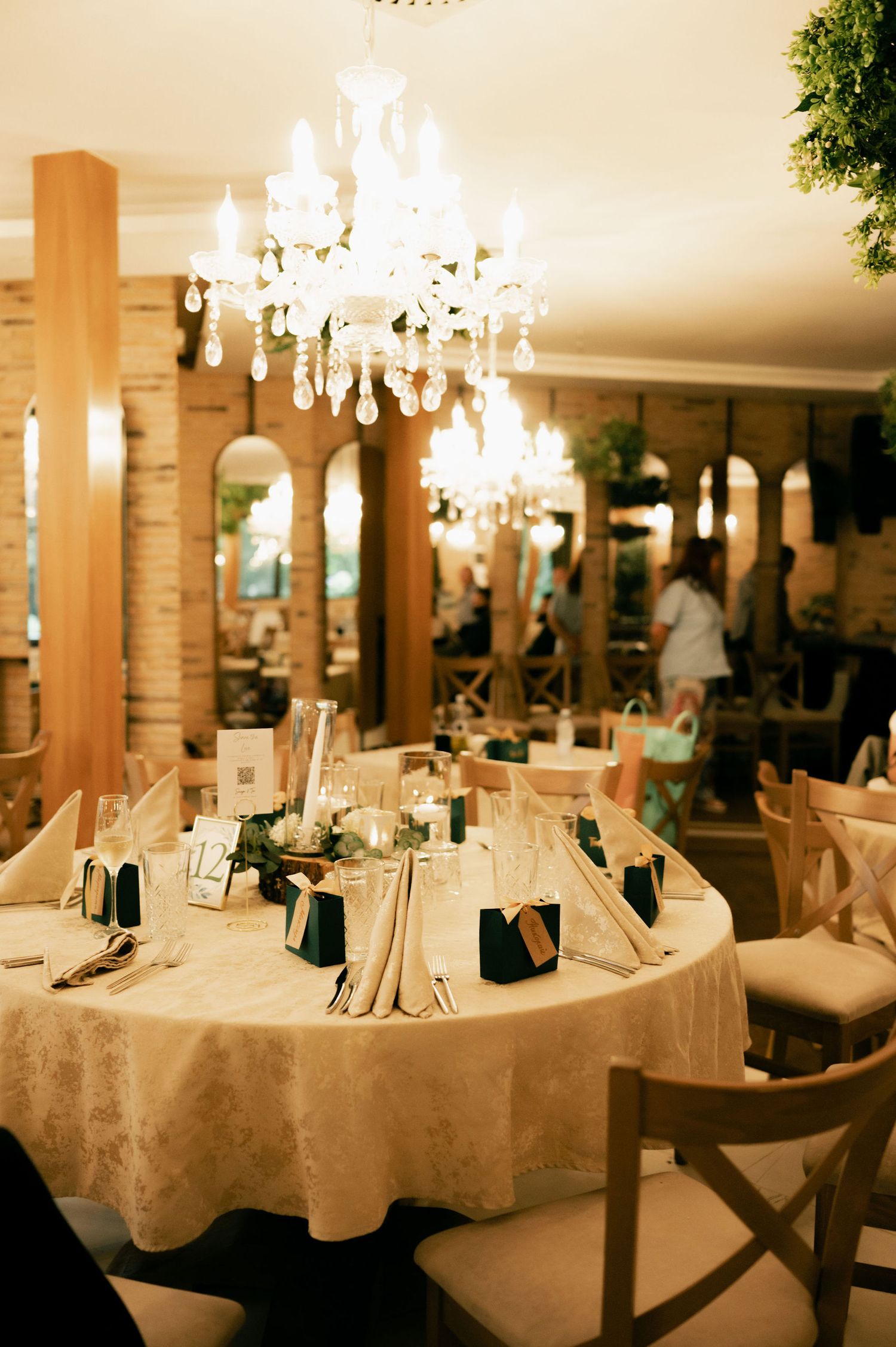 Elegant wedding reception venue with crystal chandeliers and white tablecloths set for formal dining.