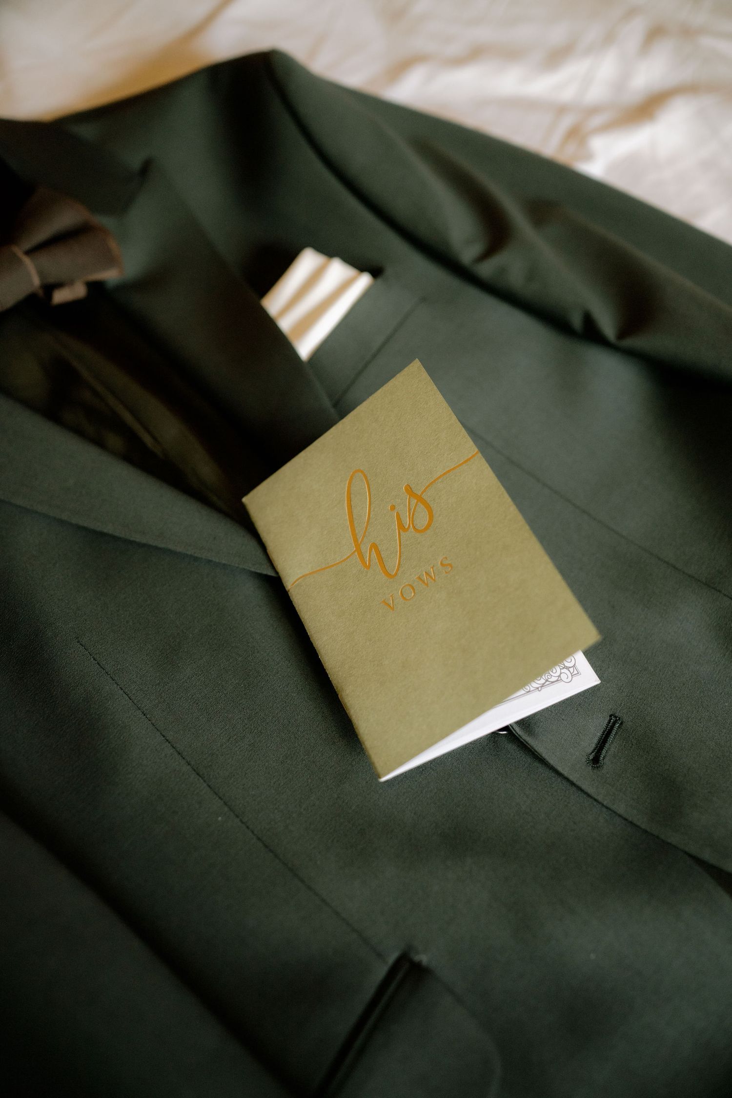 Close-up view of small gold cards placed on dark green fabric showing minimalist design details.