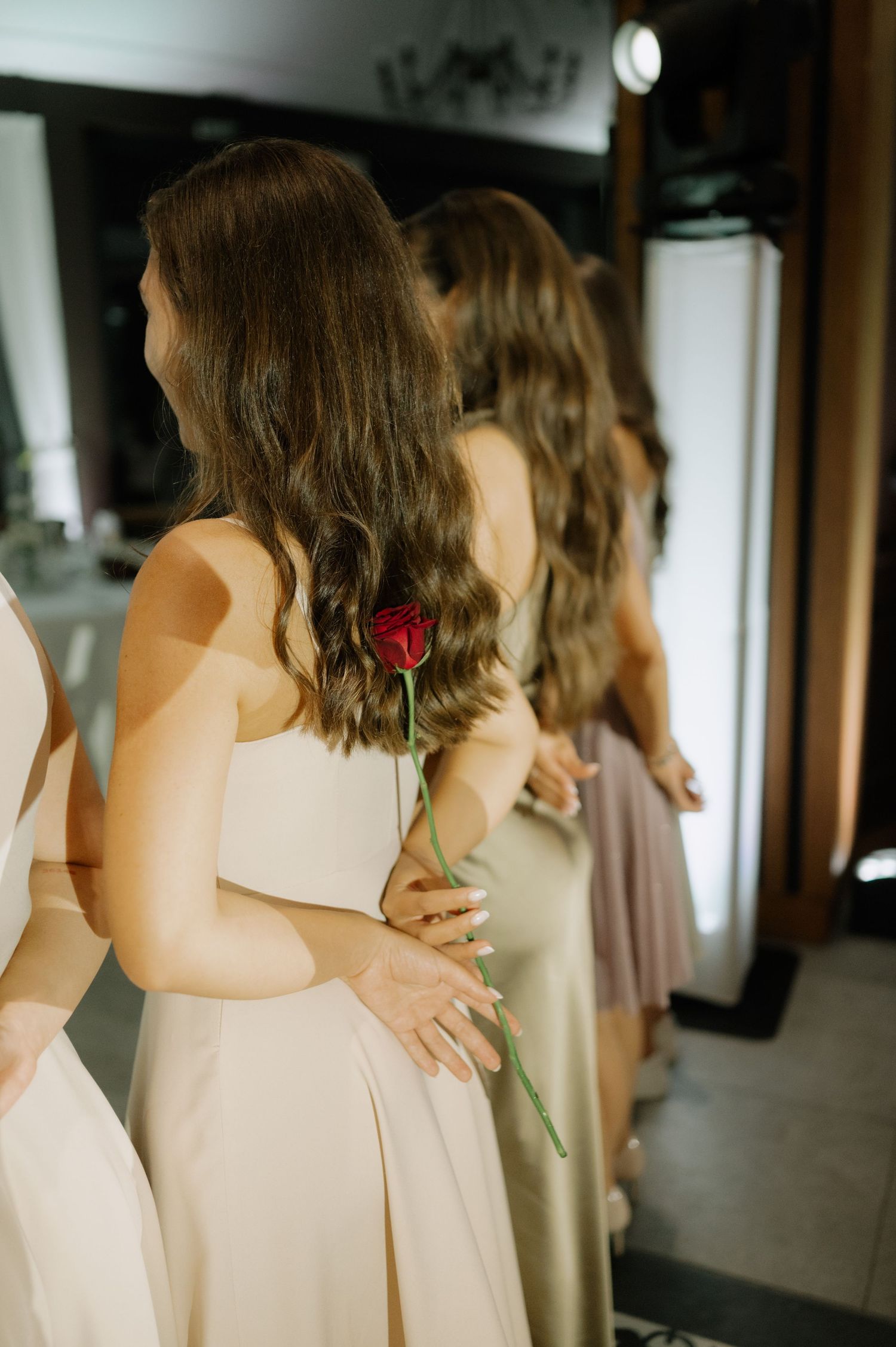 Bridesmaids in cream-colored dresses stand together in a hallway before a wedding ceremony.