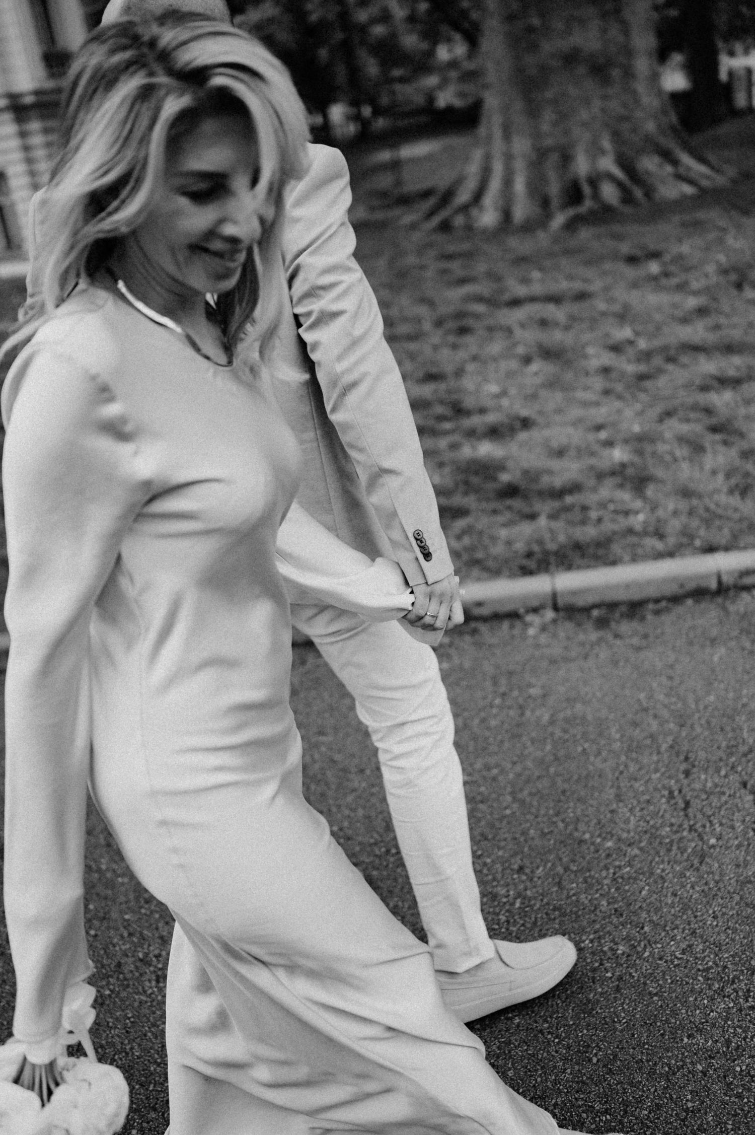 A couple shares a joyful dance moment in matching light colored outfits.