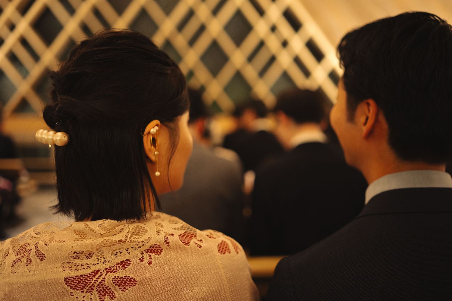 Dark silhouettes of event attendees against lattice backdrop with warm lighting.
