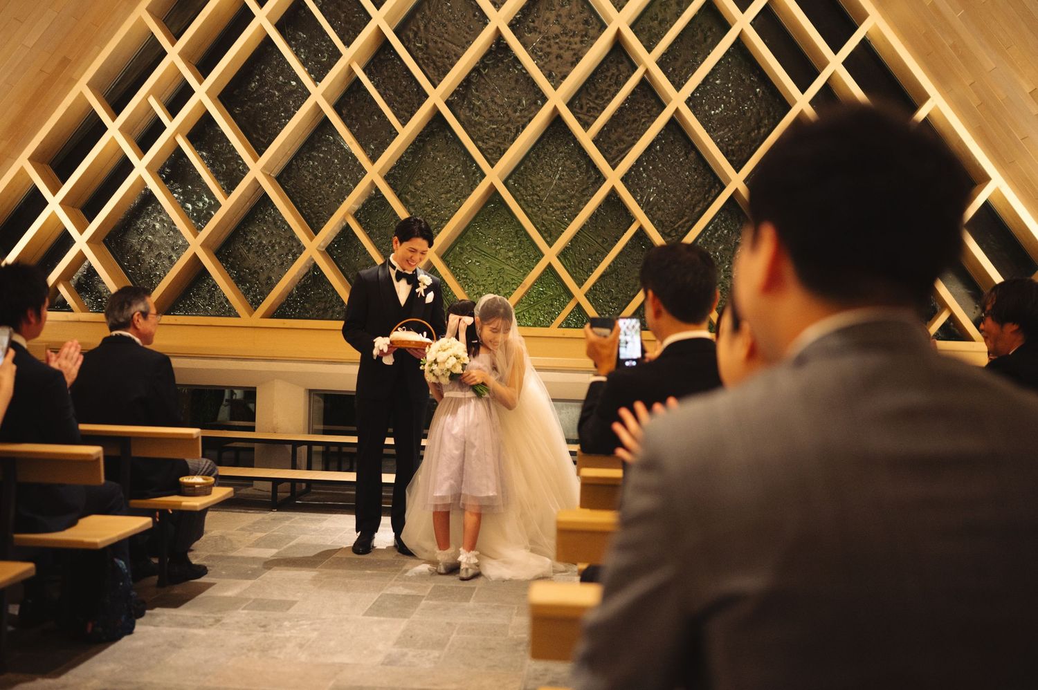 Modern chapel wedding ceremony with geometric wood panels and bench seating.