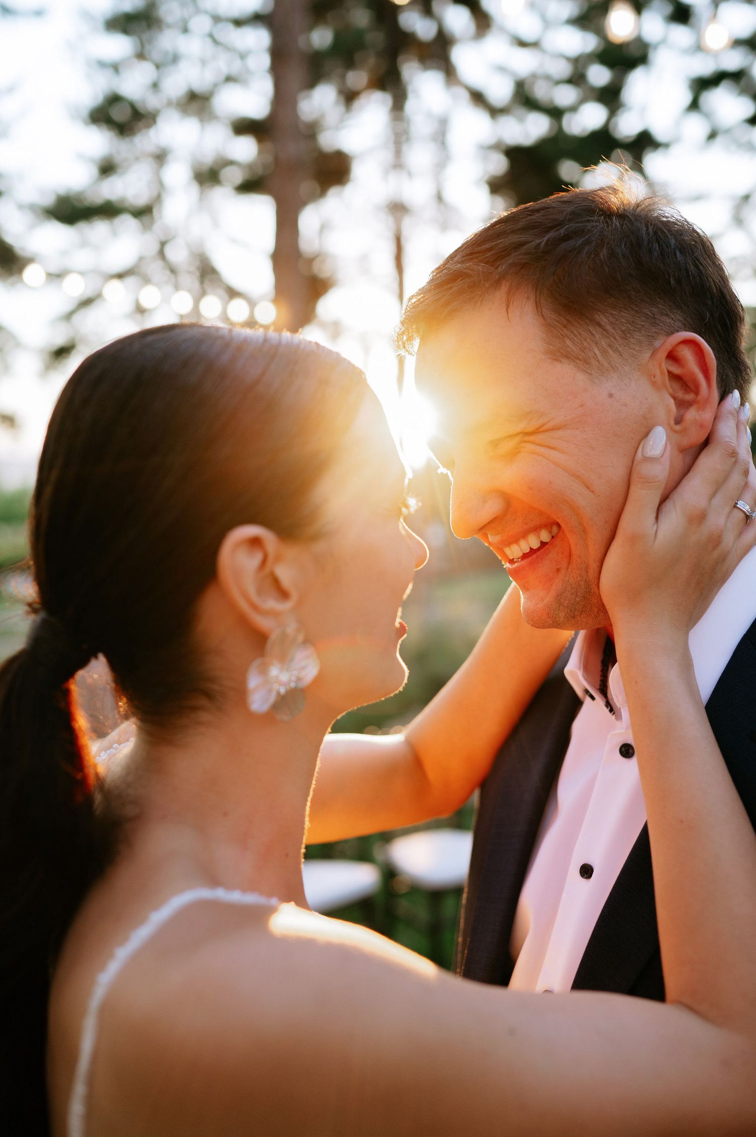 A romantic wedding moment captured in golden sunlight between a couple during their outdoor ceremony.