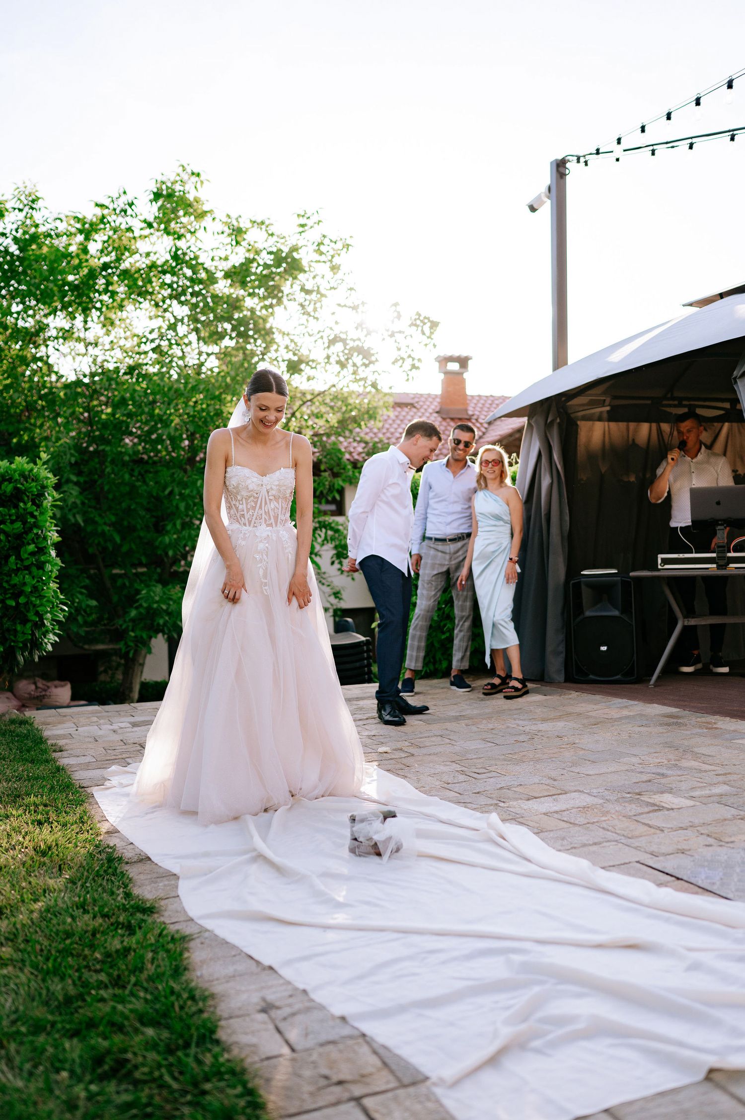 People gather around a white cloth spread on outdoor stone patio during celebration.