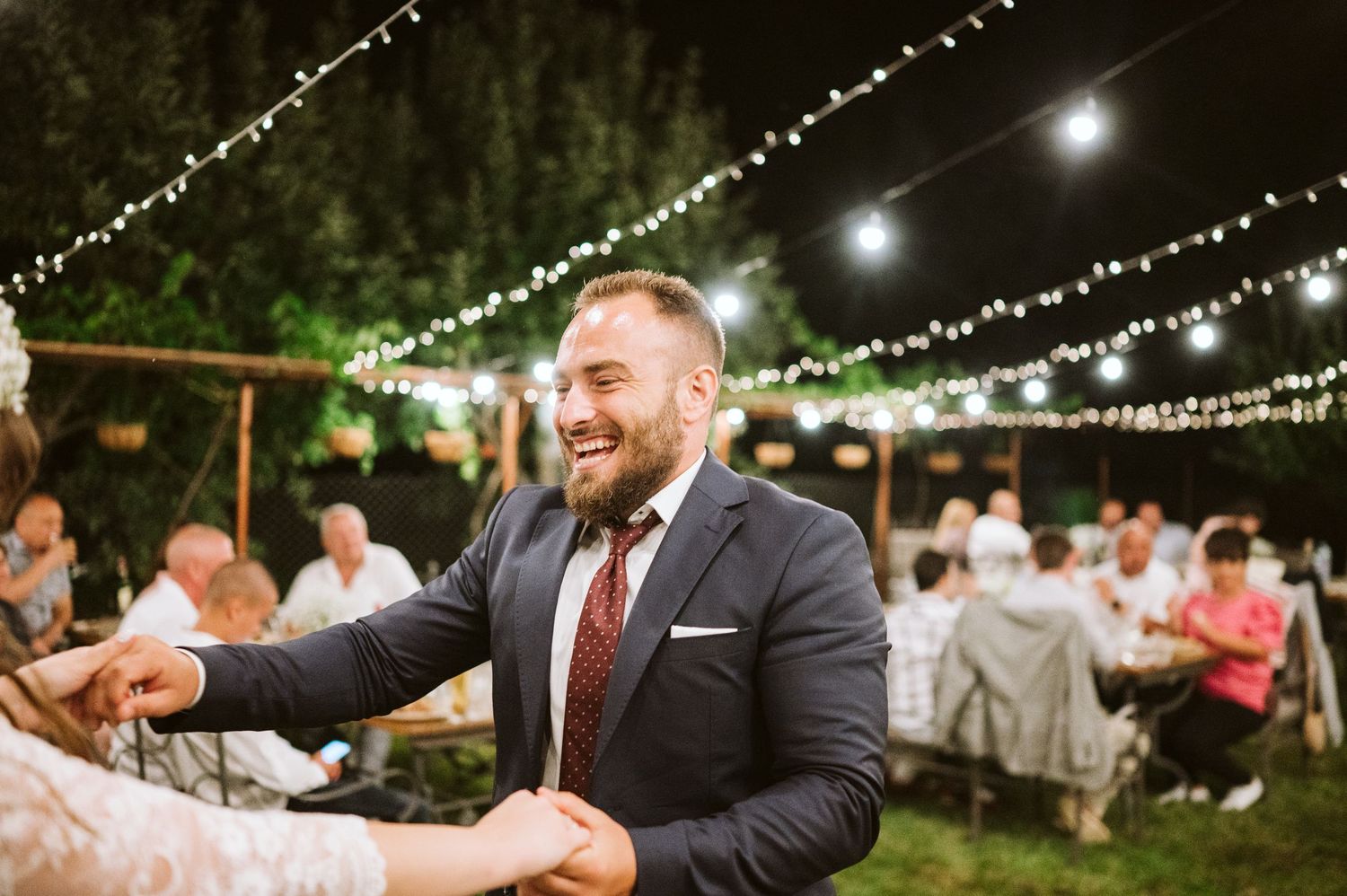 Wedding guest dancing under string lights at outdoor reception.
