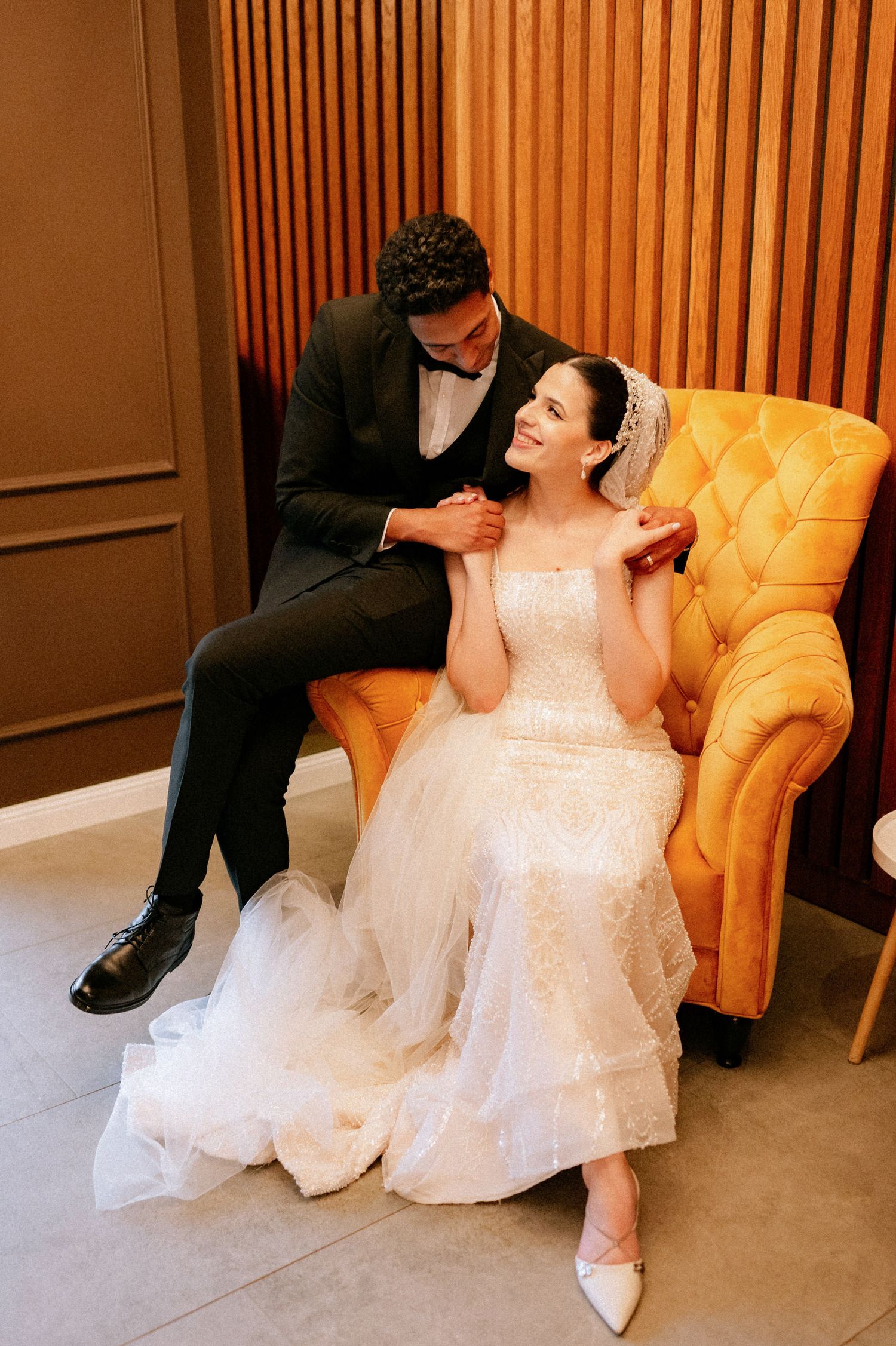 Wedding photography session featuring elegant white dress and yellow tufted chair.