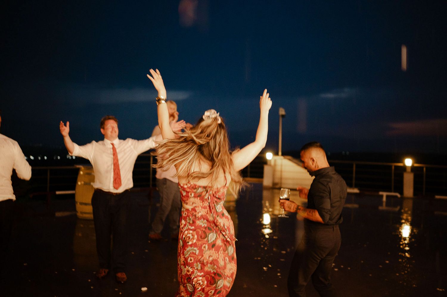 Guests enjoying themselves with raised arms on an outdoor dance floor at dusk.