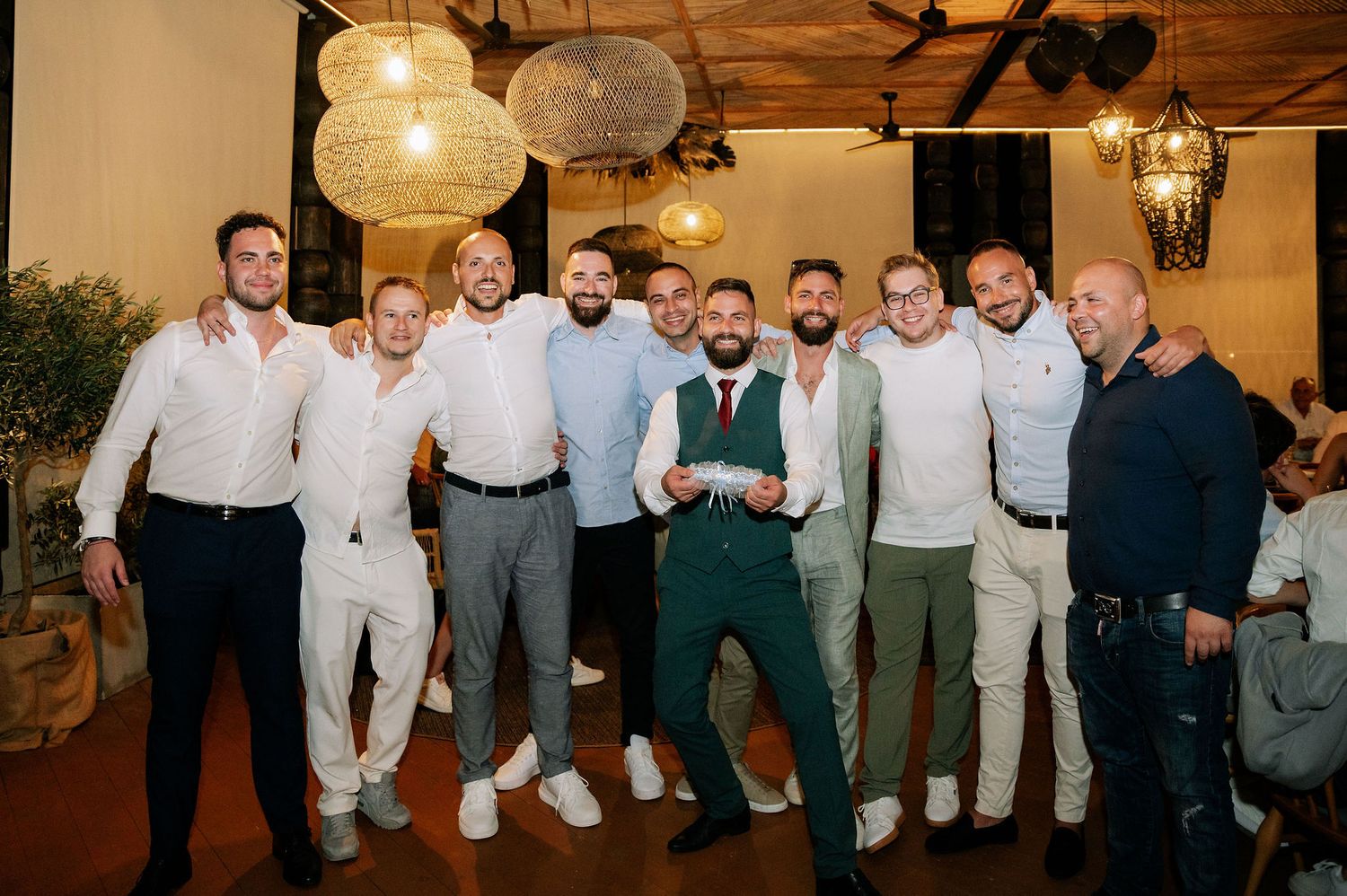Group of men in matching formal attire striking playful poses at a wedding event.