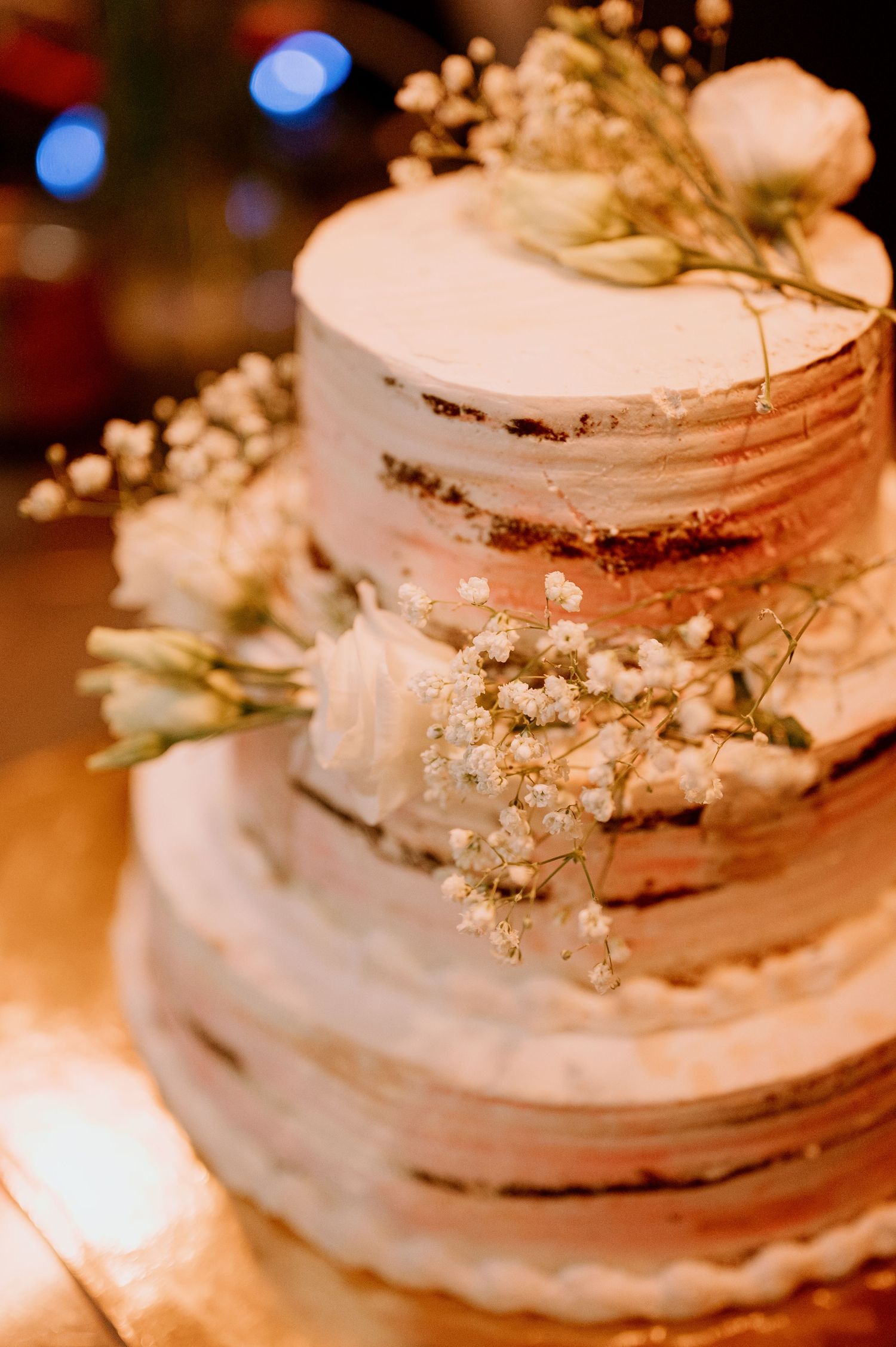A tiered white wedding cake decorated with delicate baby's breath flowers and textured frosting.