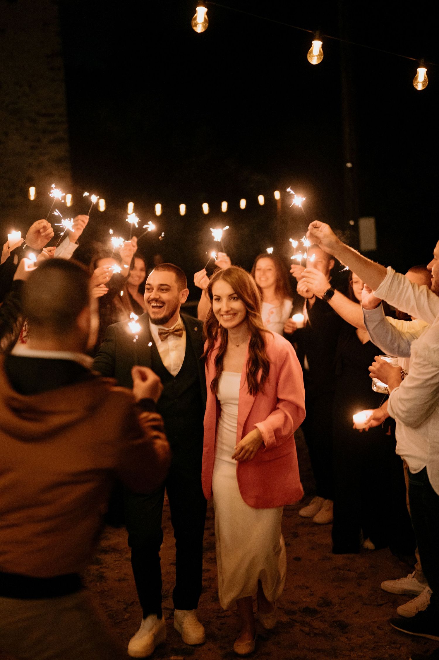 Celebratory dance moves under festive string lights at an outdoor evening event.