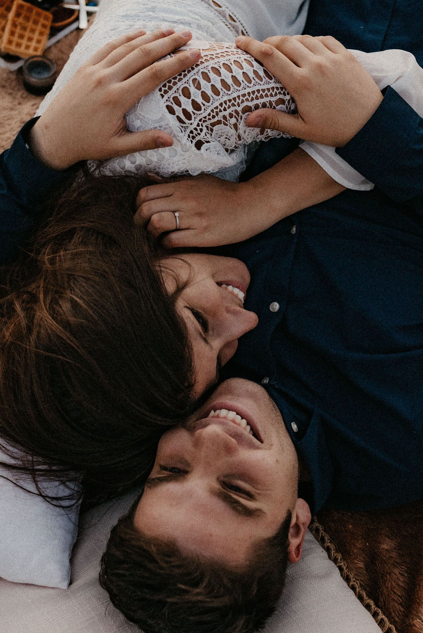 Couple lying down together sharing an intimate moment with joyful laughter.