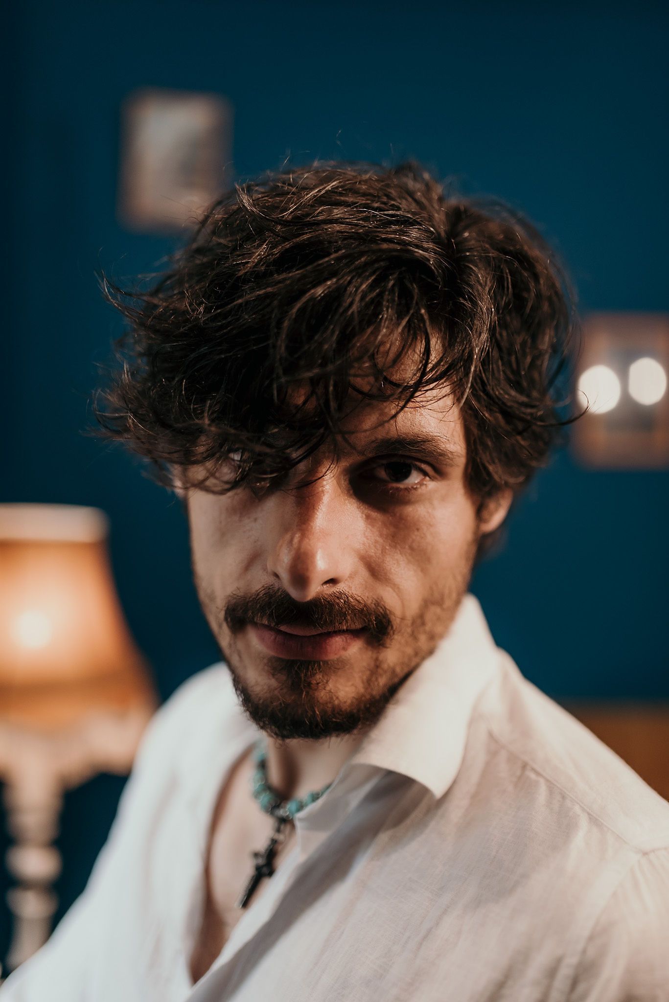 Portrait against deep blue wall with warm lamp lighting.