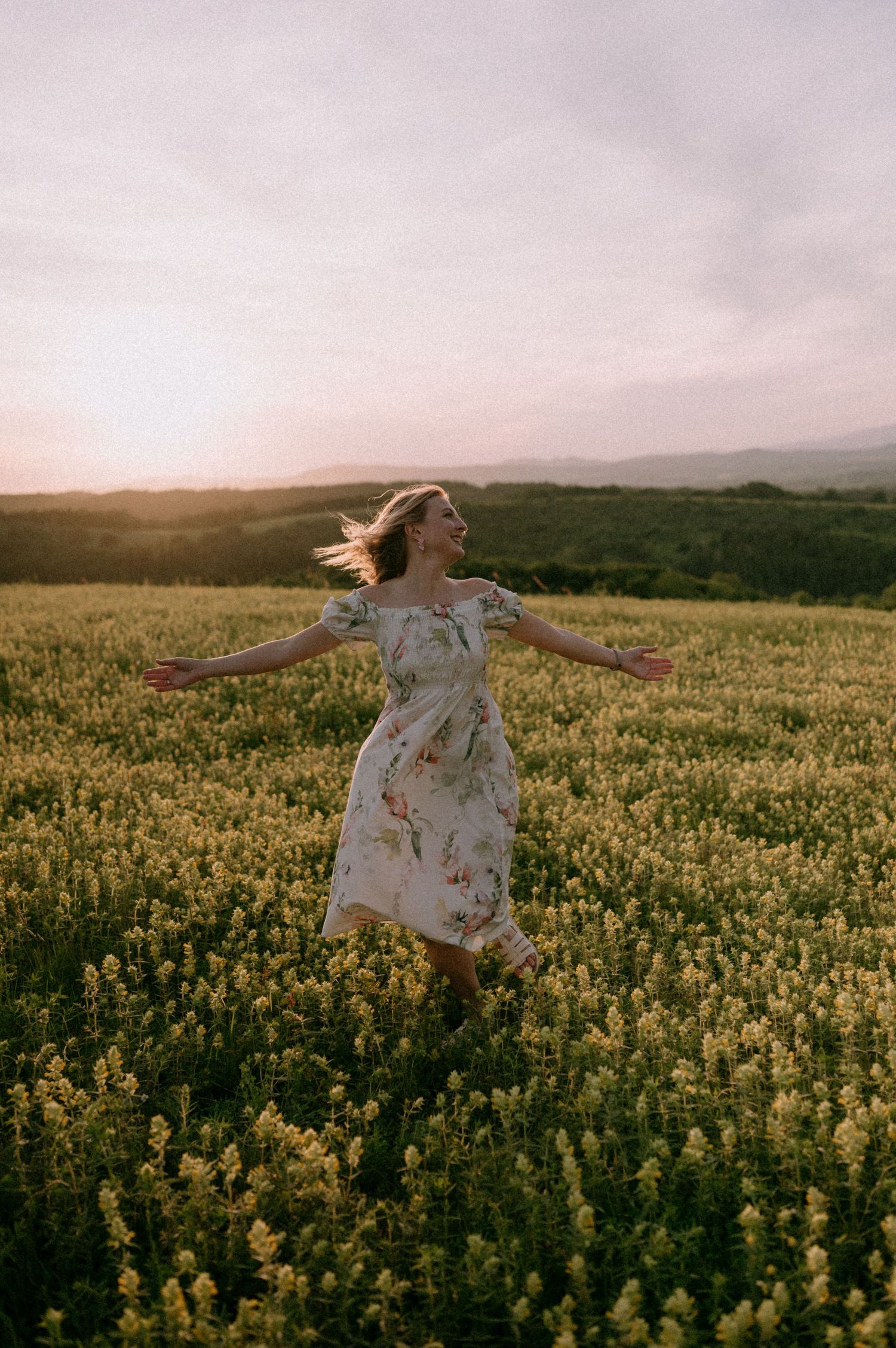 Figure in white dress dancing freely through a field of yellow flowers.