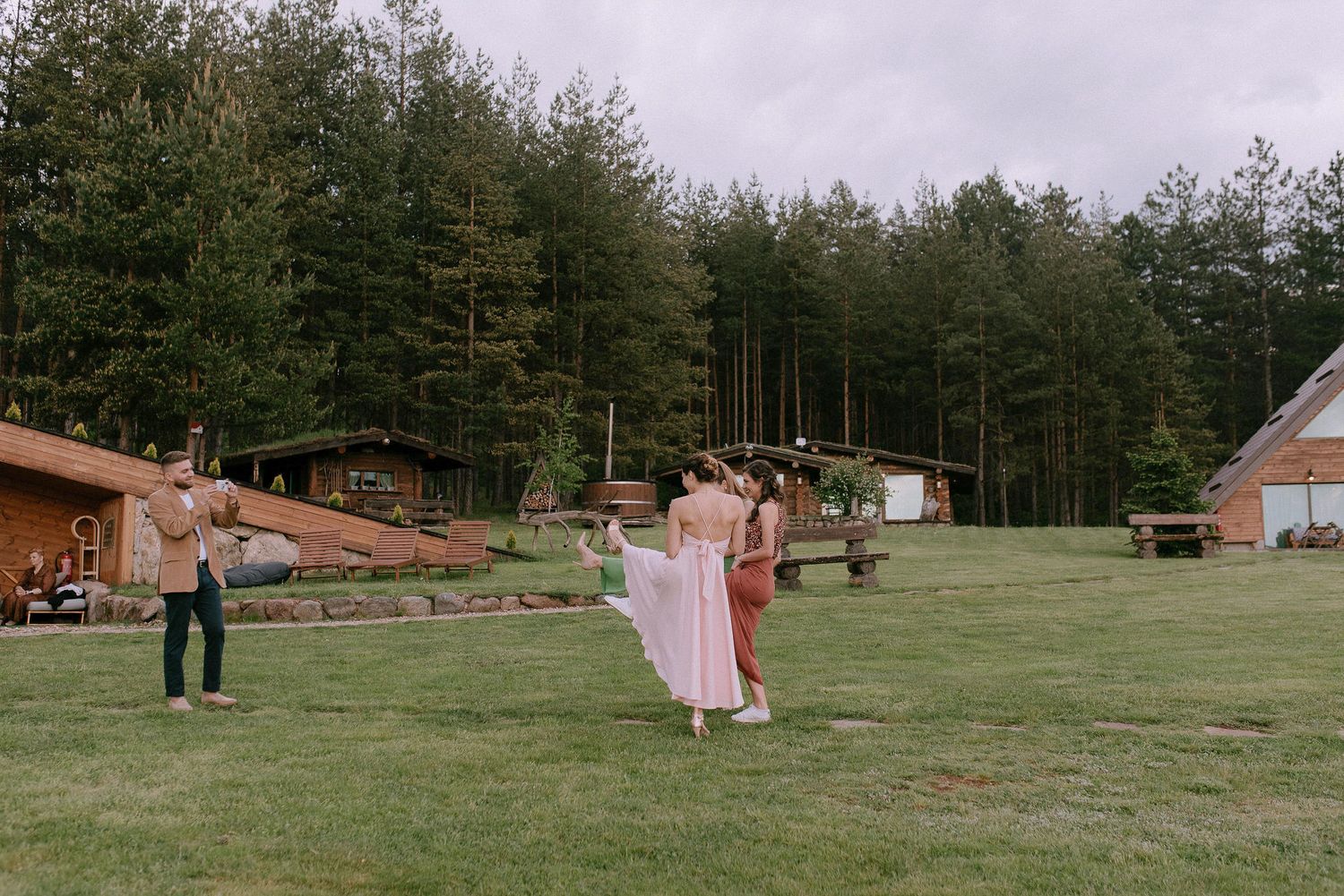 Wide landscape view of rustic buildings and gathering spaces on a forested hillside.