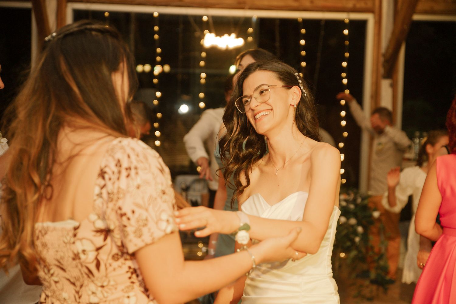 People dancing and celebrating at a wedding reception with warm lighting and festive atmosphere.