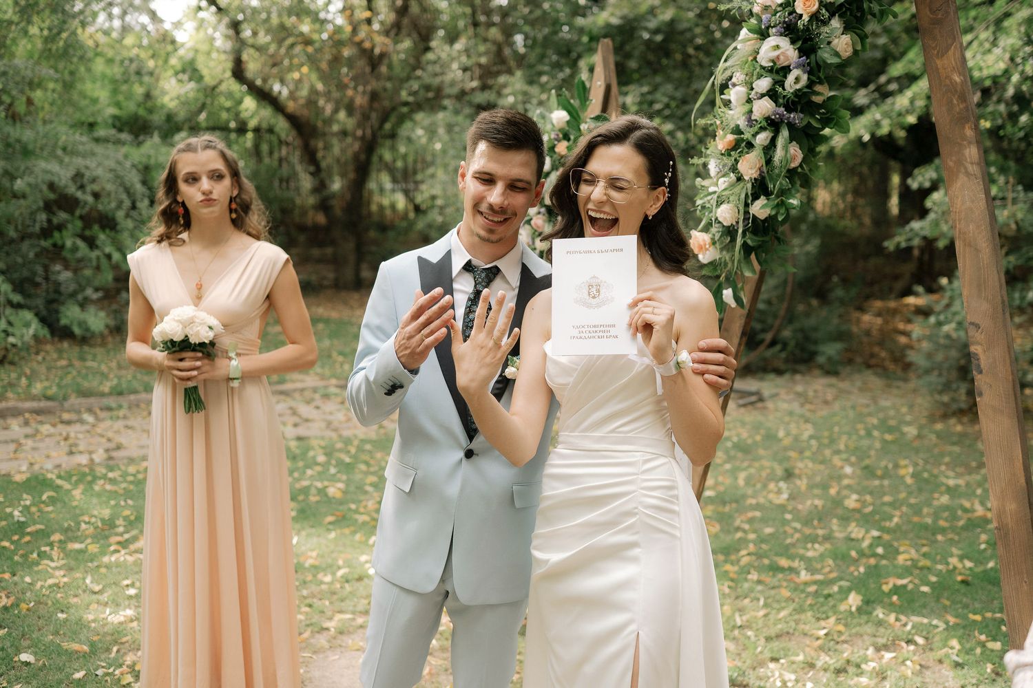 A romantic wedding scene unfolds in a lush garden setting with bridesmaids in peach dresses and a bride in white.