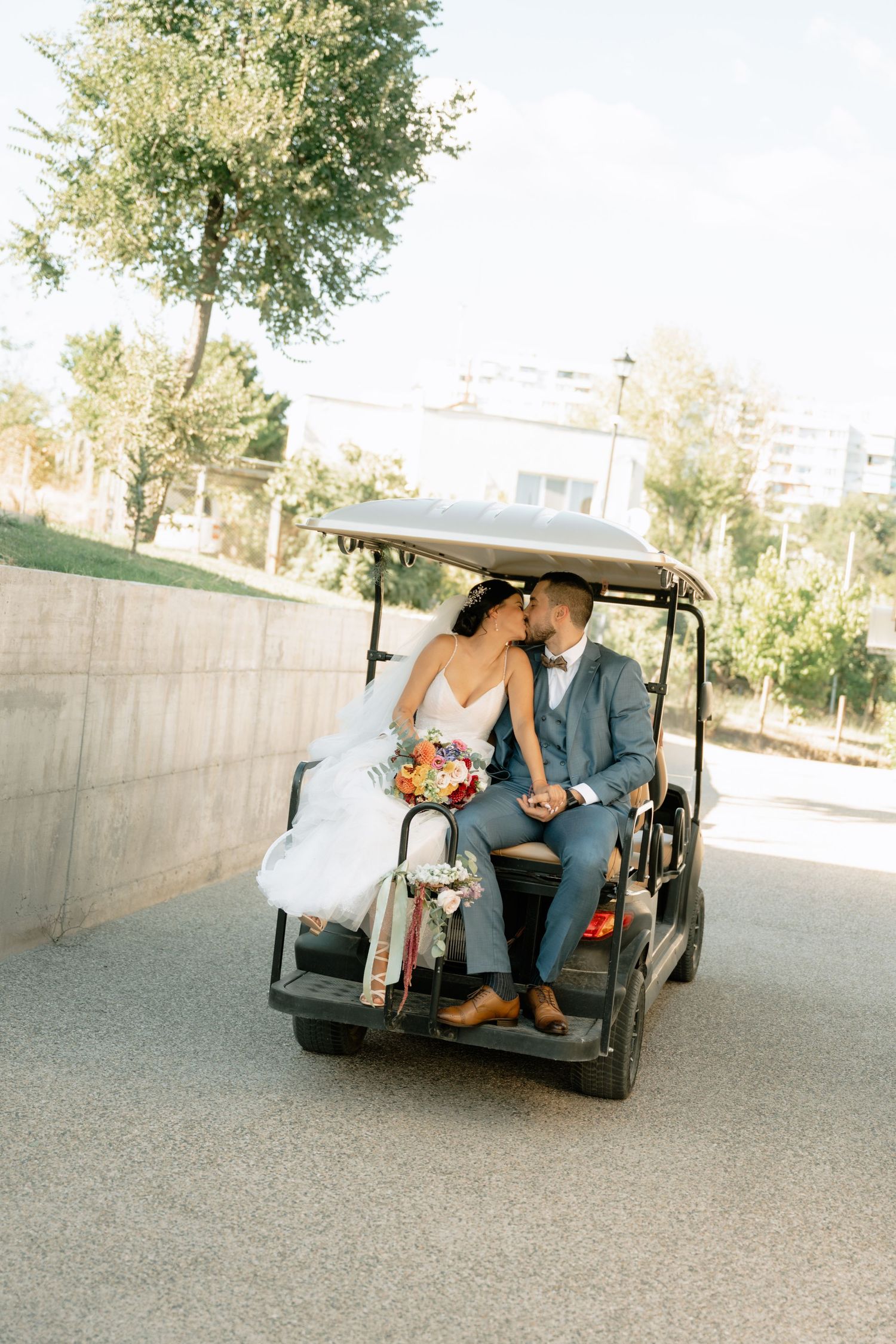 Wedding couple shares romantic moments while seated in a vintage black golf cart during their special day celebration.