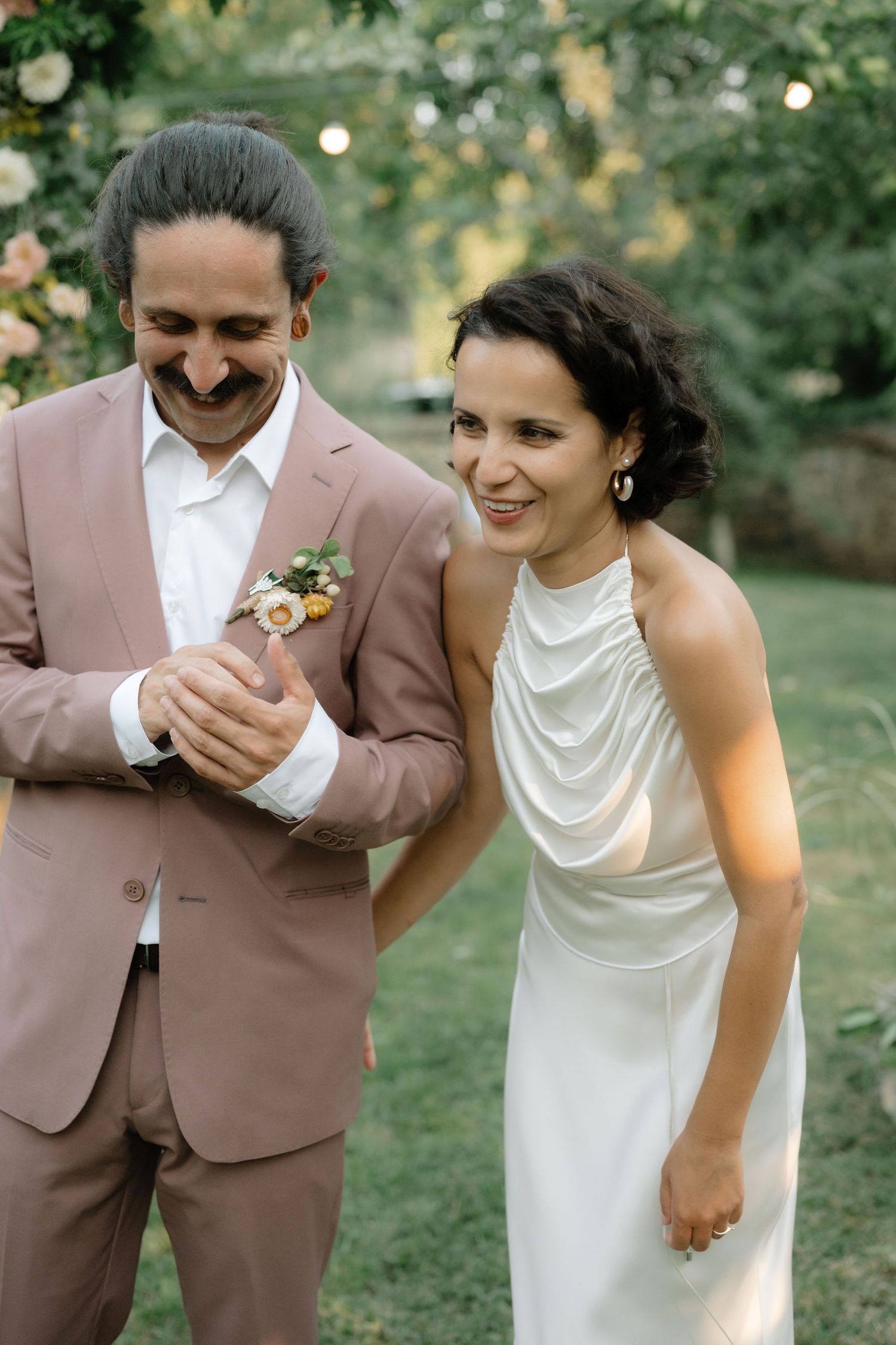 A couple in wedding attire share playful candid moments in a garden setting during their photoshoot.