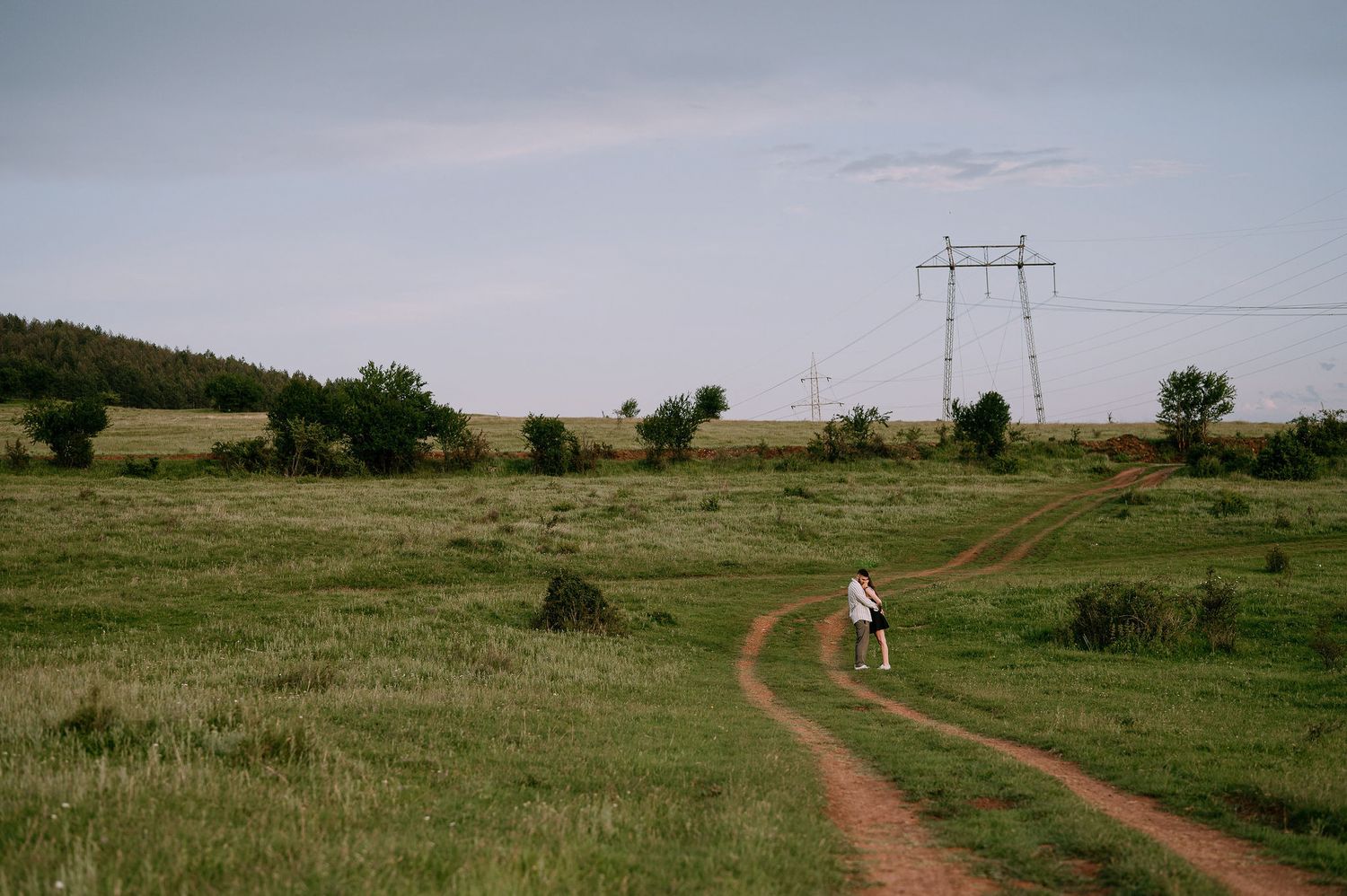 A series of dirt roads winding through grassy rural landscapes with power lines and scattered trees in the distance.