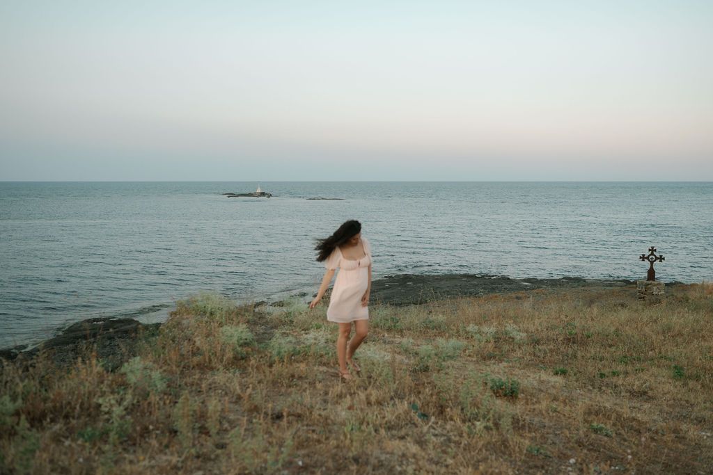 A serene coastal landscape with green grass overlooking the ocean during sunset.
