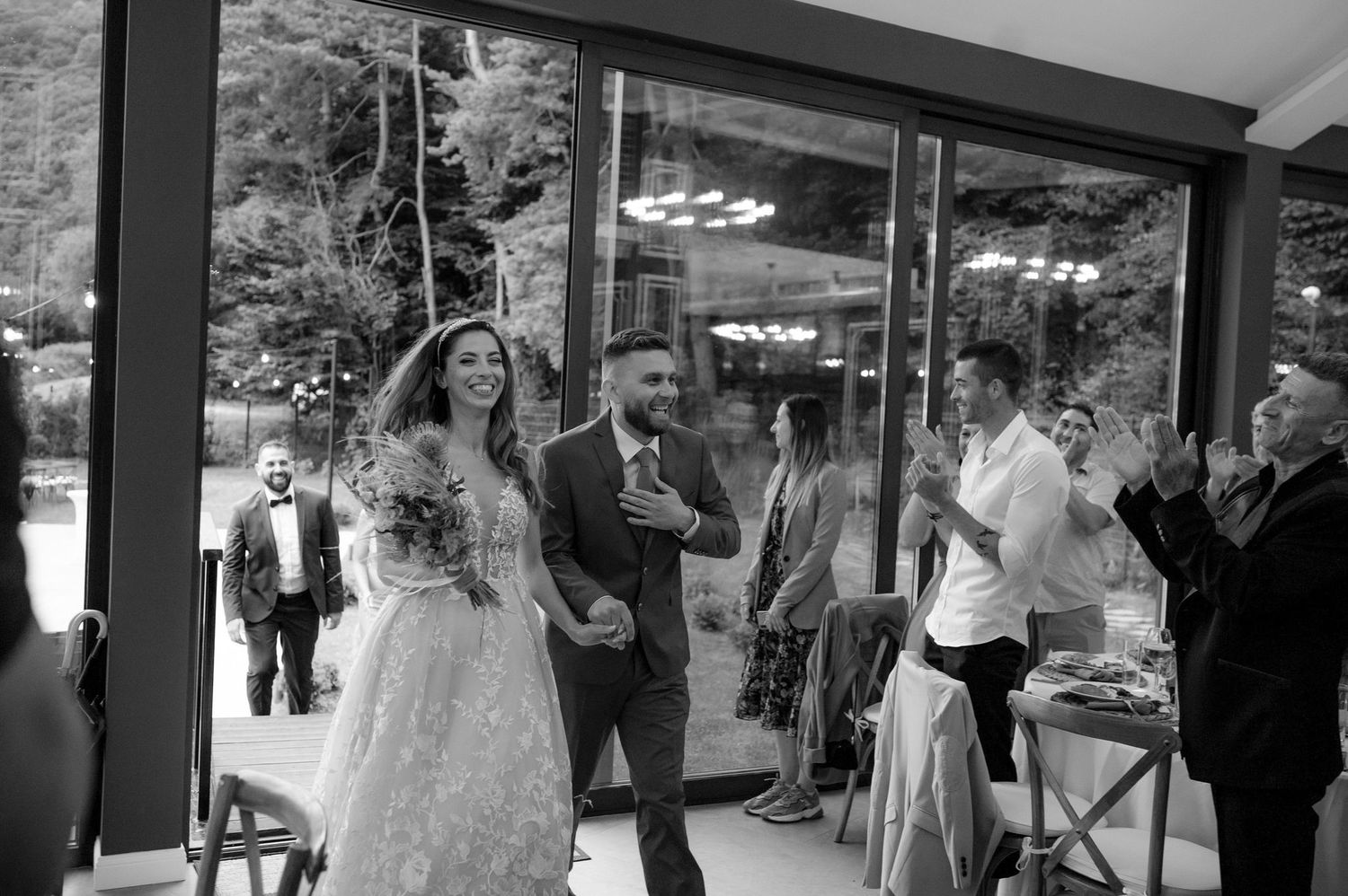 A panoramic view of a wedding reception venue with guests mingling and dining under elegant lighting.