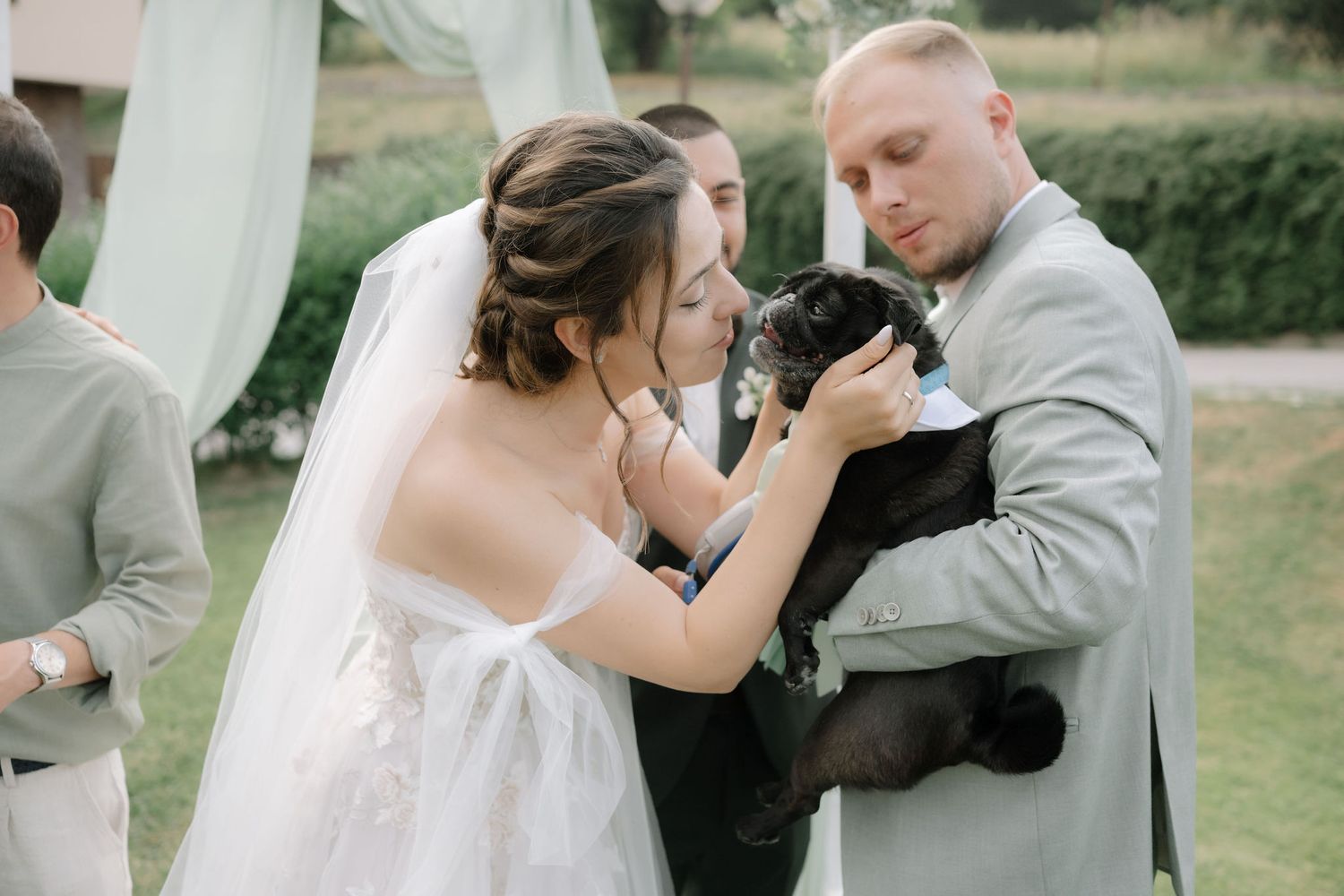 Wedding party members in pink and gray attire share candid moments during outdoor celebration.