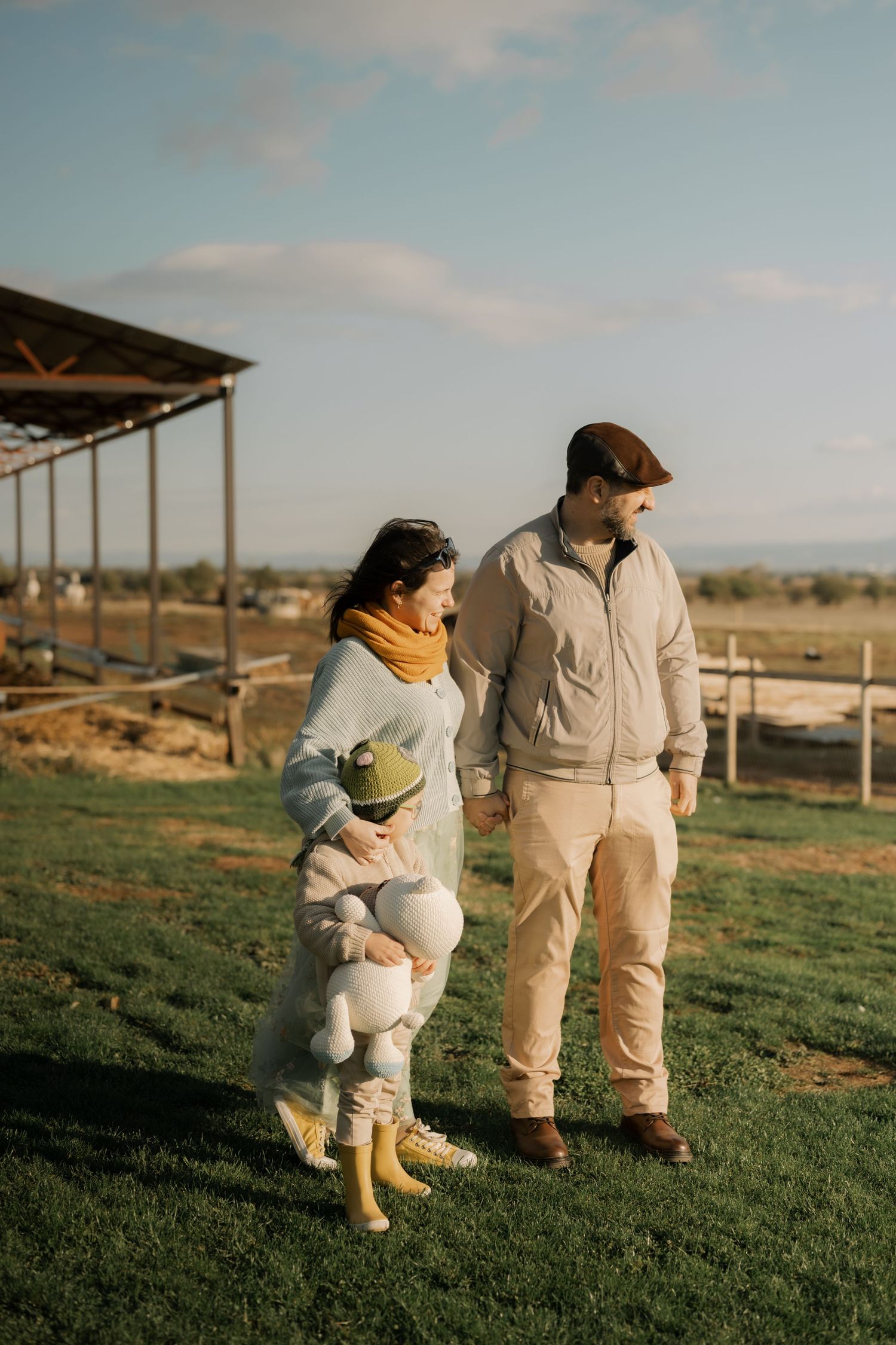Beekeepers in protective suits walk together across a grassy field at sunset.