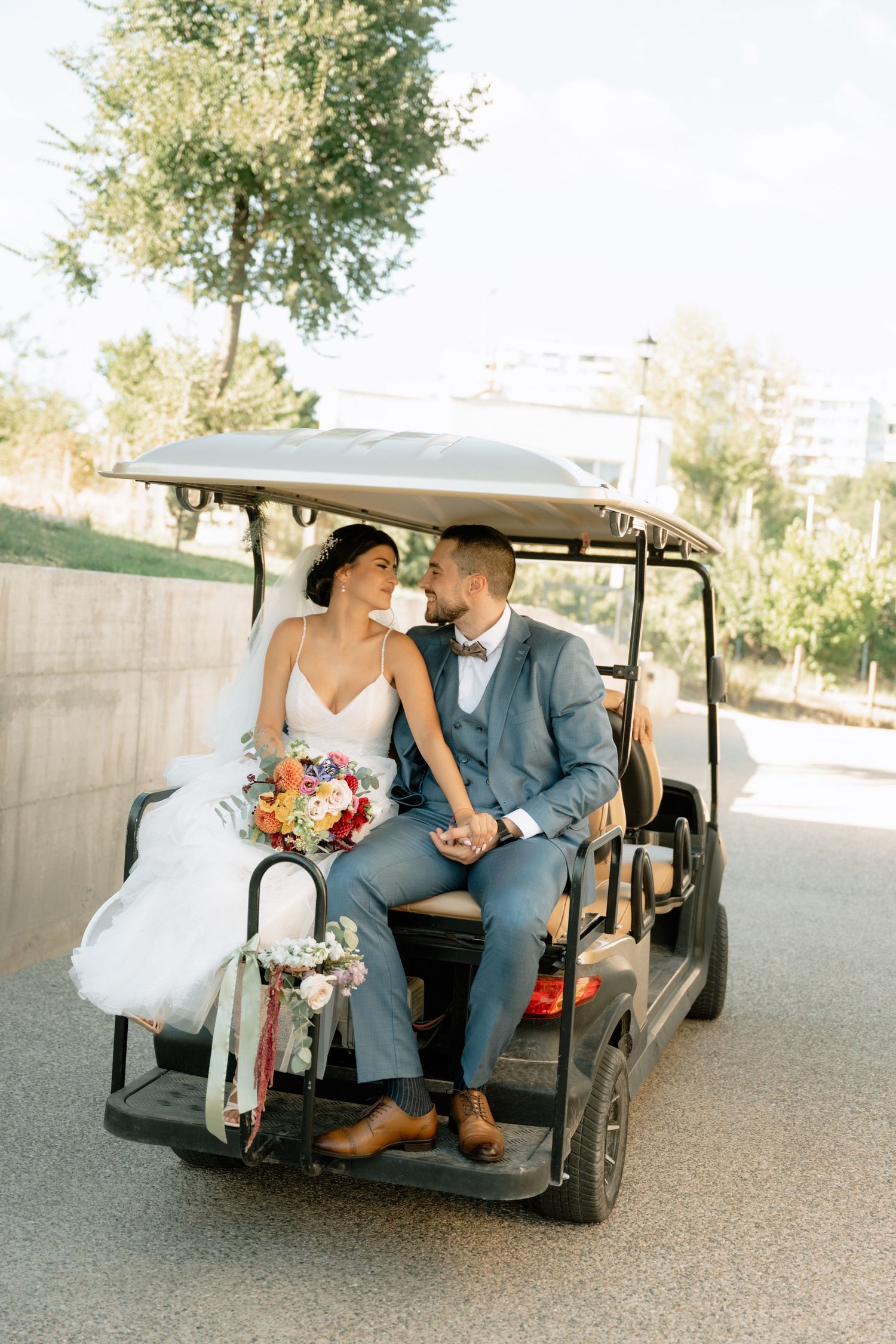 A romantic moment captured in a vintage golf cart showing a couple in wedding attire sharing an intimate moment.
