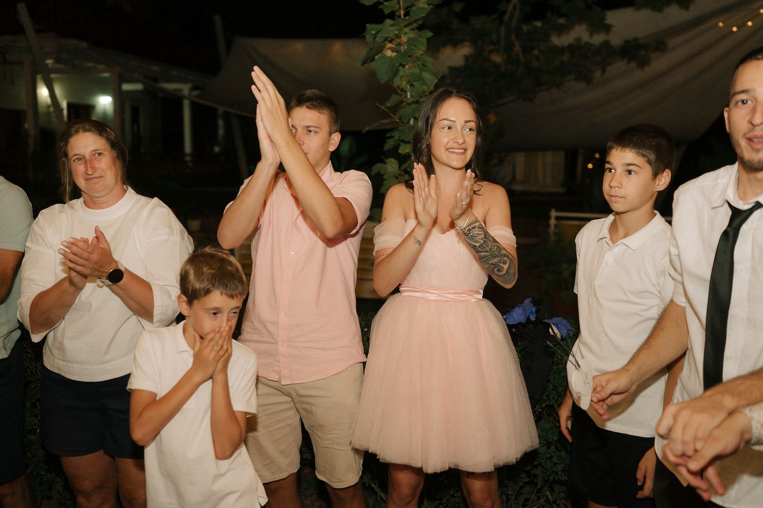 A group of people in formal attire dance together at an evening celebration event.