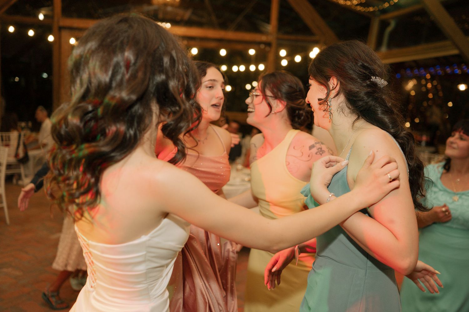 People dancing together at a festive outdoor party with string lights illuminating the evening atmosphere.
